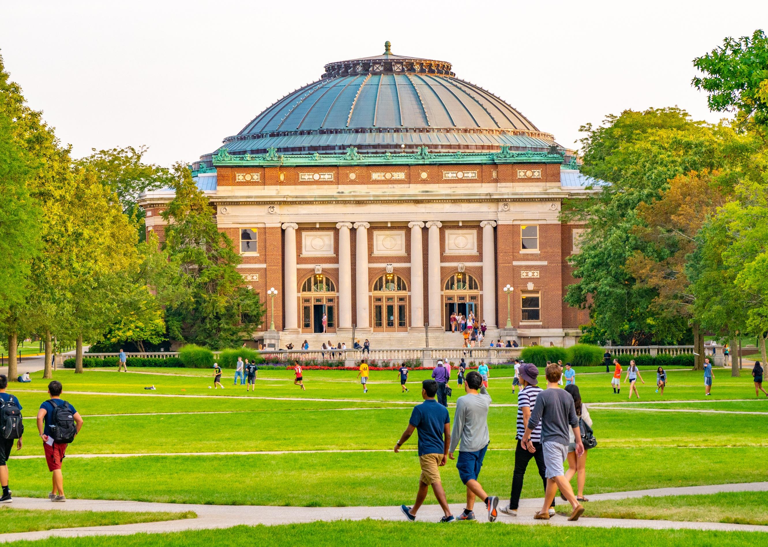 Students walk outdoors on lawn of the campus quad of Urbana Champaign.