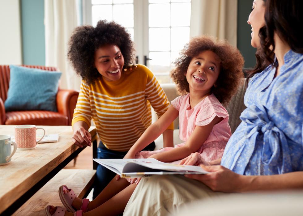 Two moms reading book with daughter