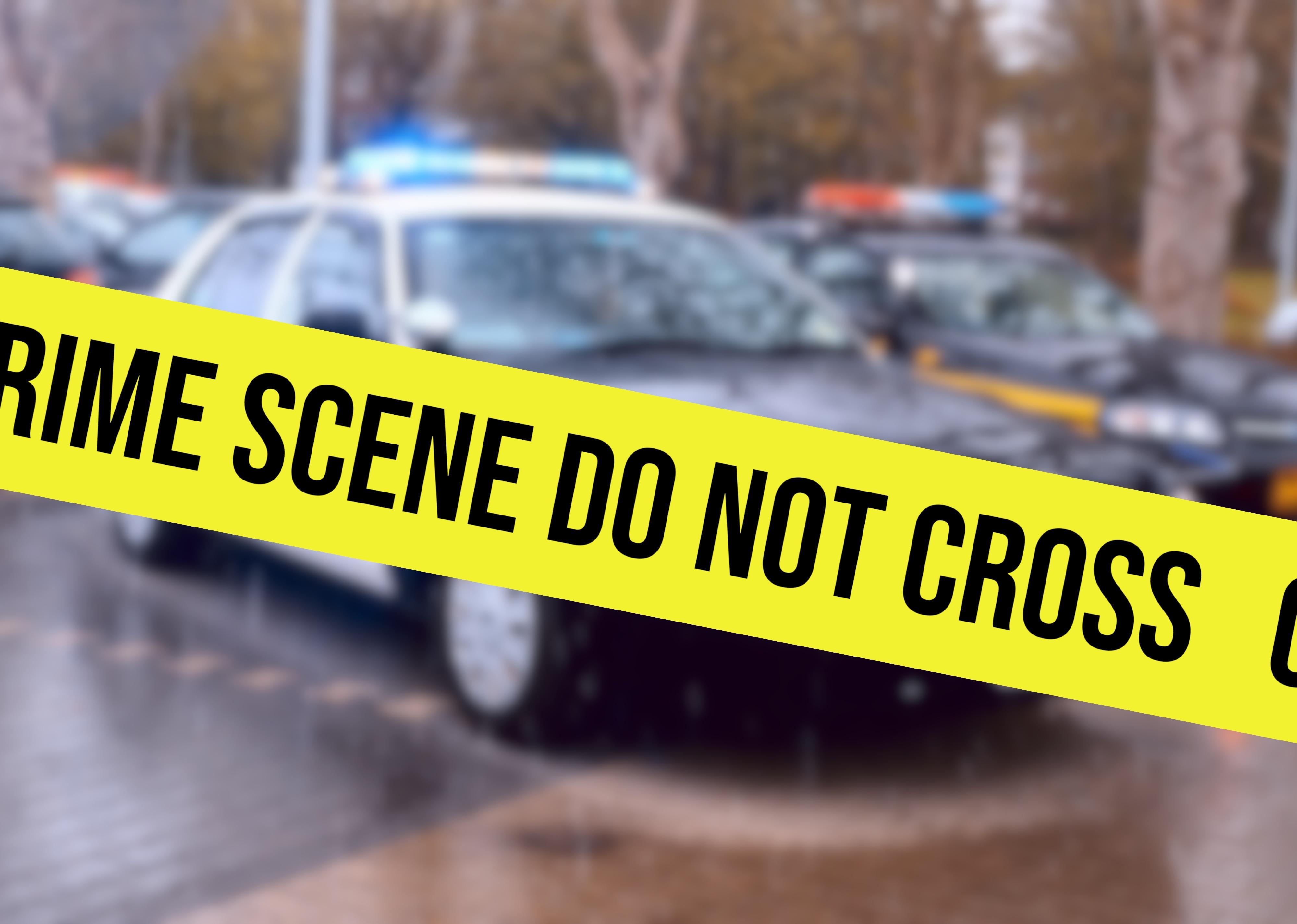 Two police cars and cordon at crime scene.