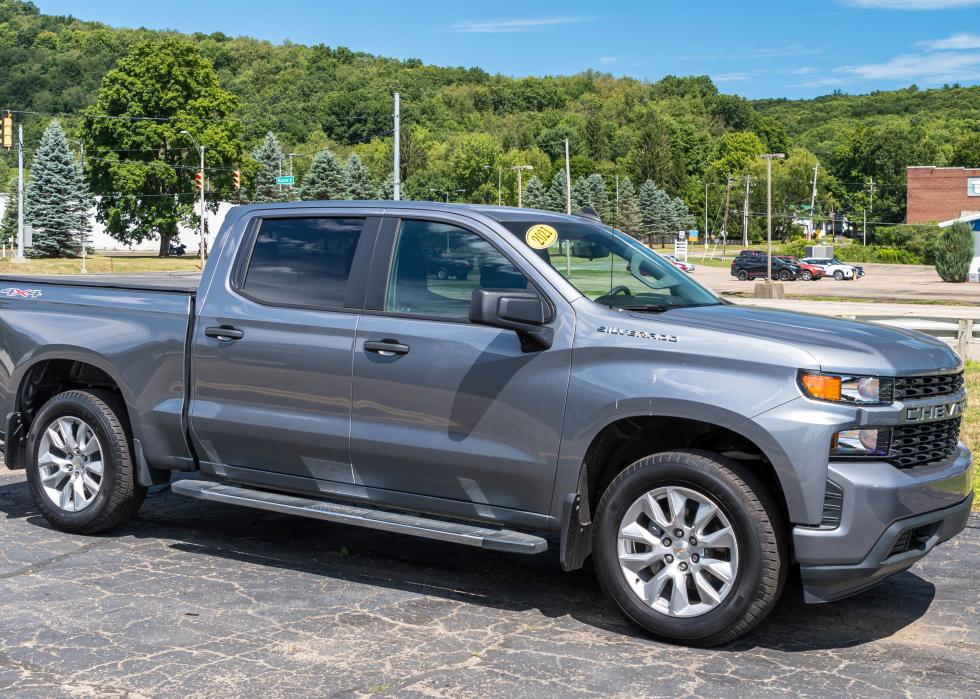 A used, gray four door Chevrolet truck for sale at a dealership.