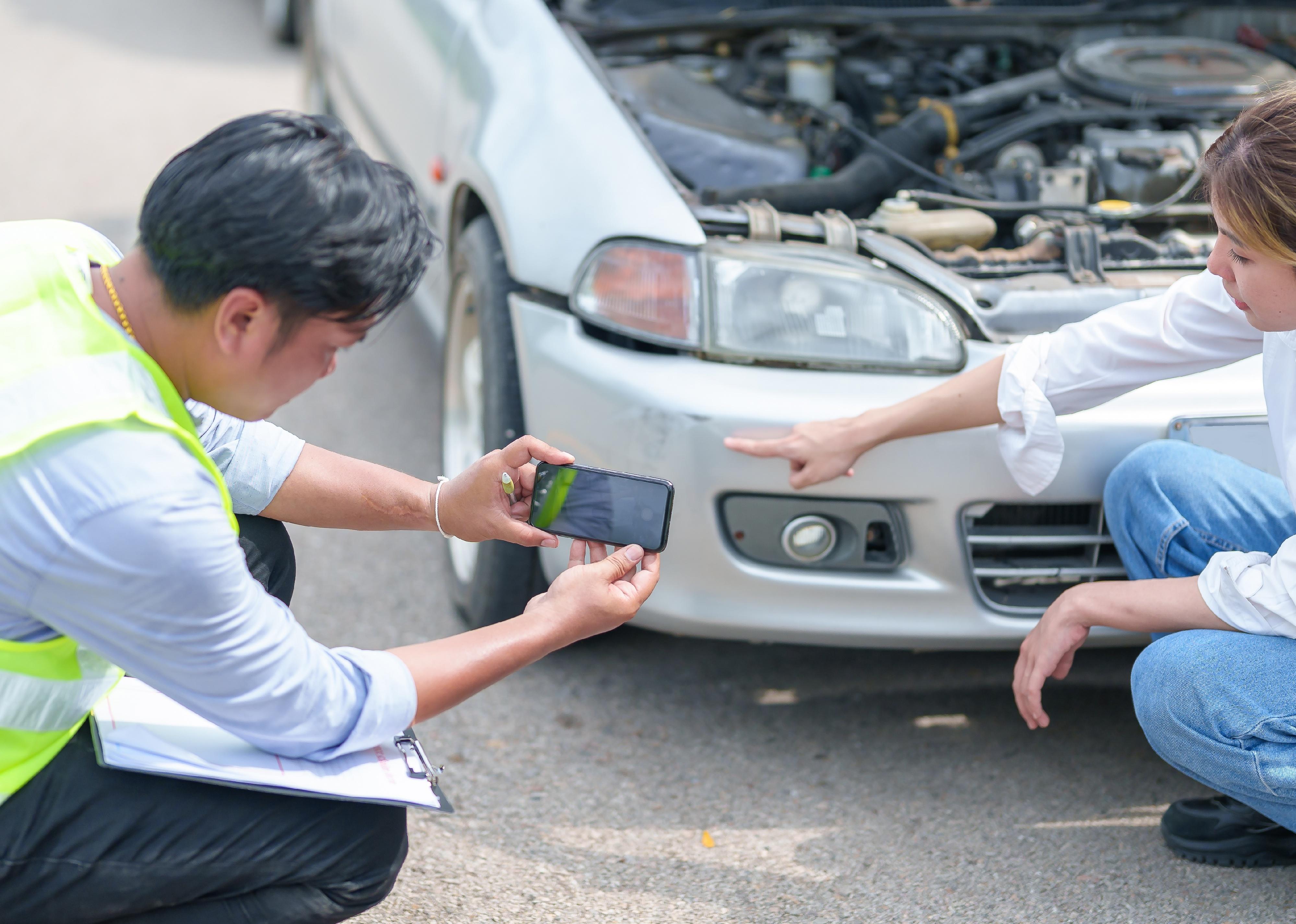 Insurance agent takes pictures of crashed car on his smartphone