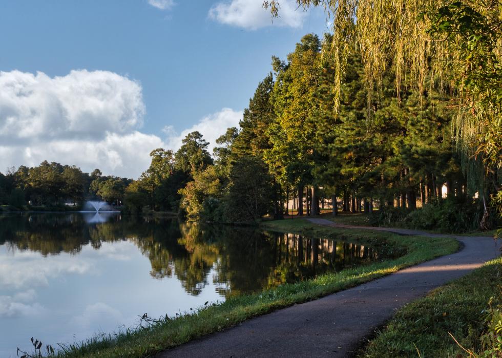 Walking path by lake with fountain and reflections off water in Innsbrook.