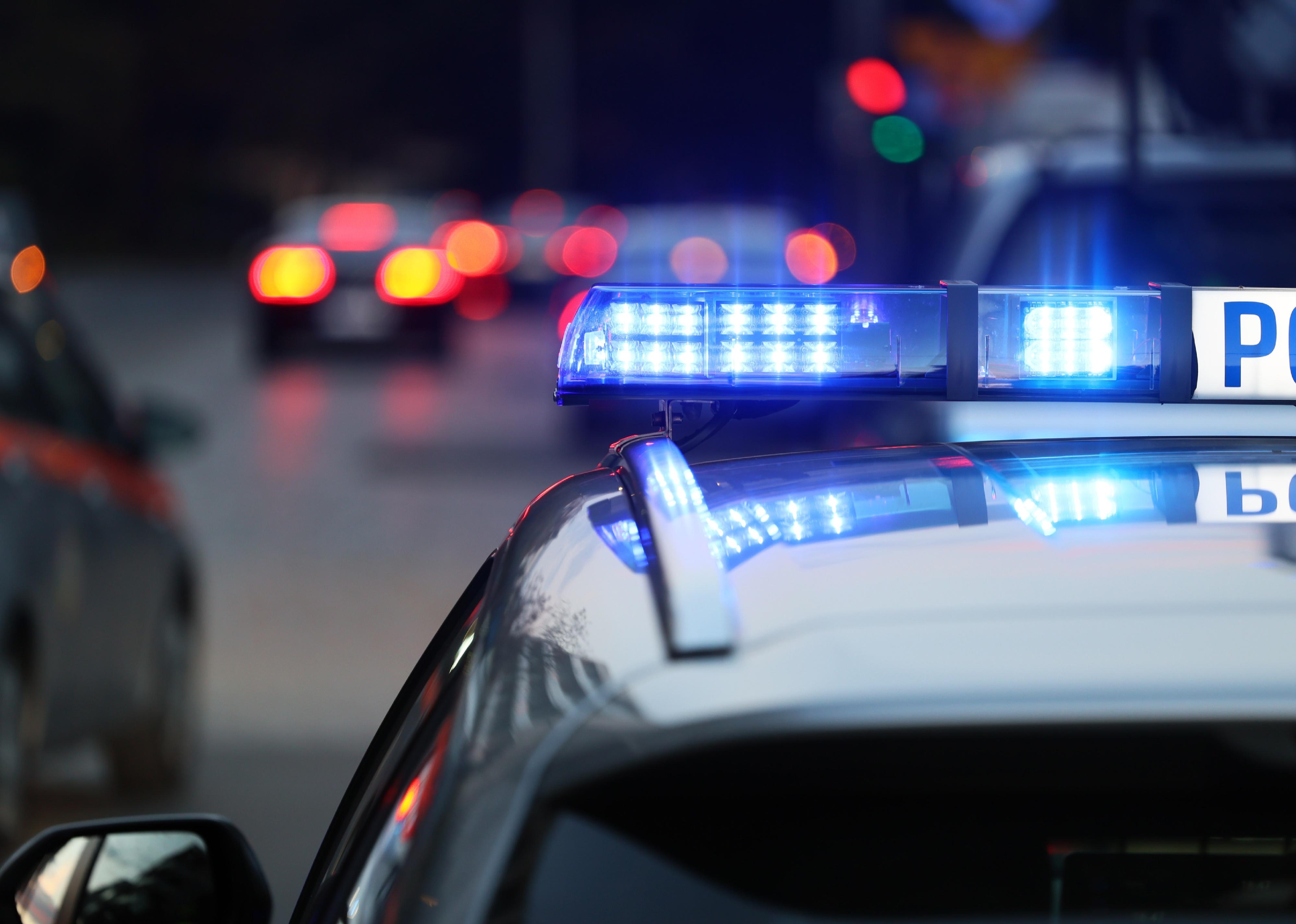 Police patrol car with blue flashing light on the roof.