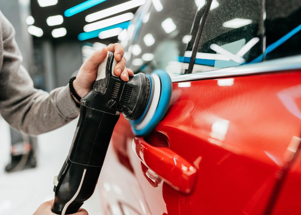 Man polishing car in a modern car workshop. 
