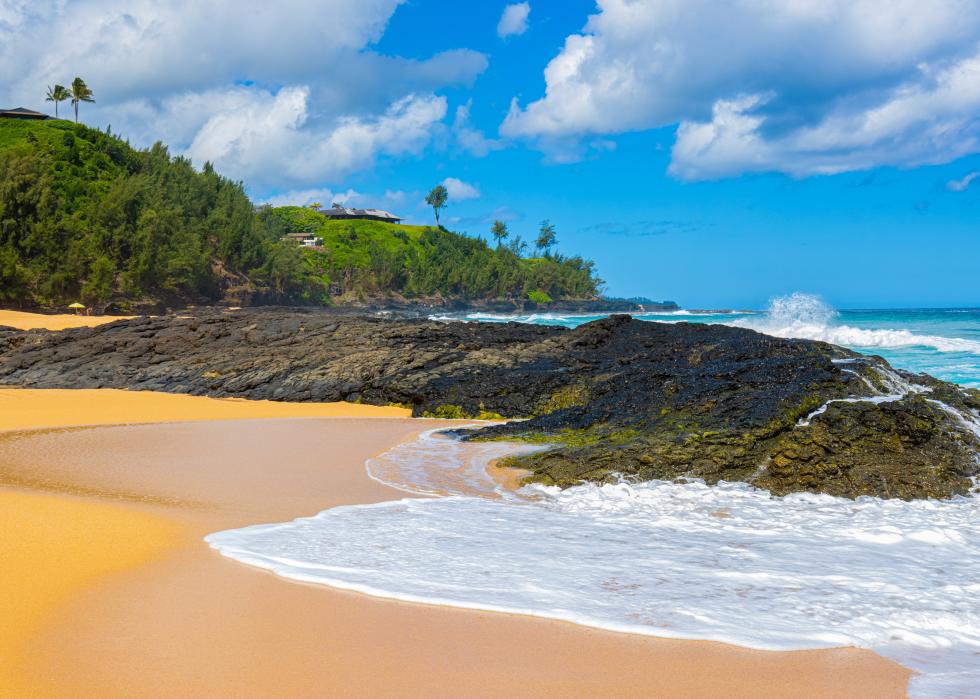 Waves crash over exposed lava reef, Kauapea Beach.
