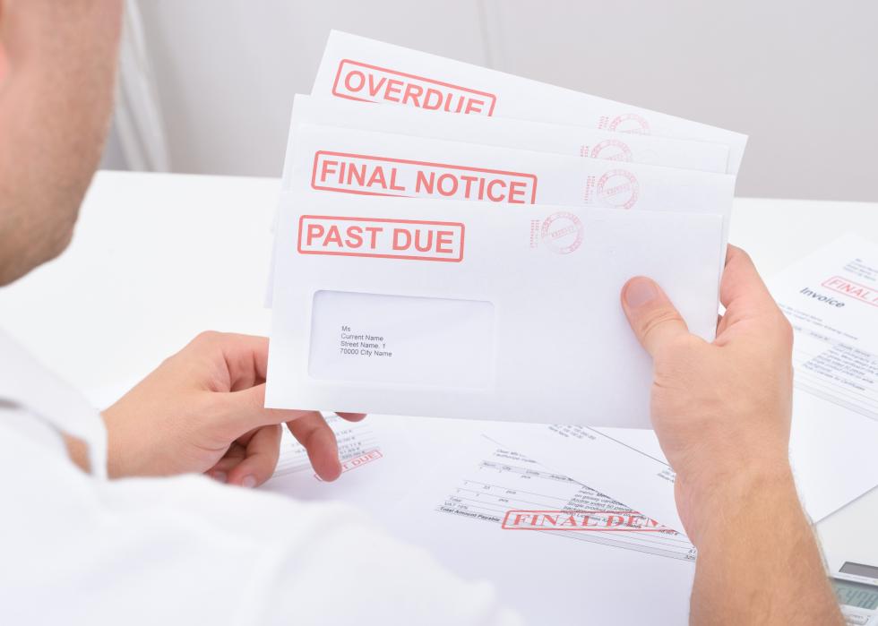 Close-up of a man holding past due statements