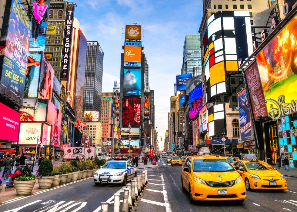 Times Square intersection with traffic and visitors.