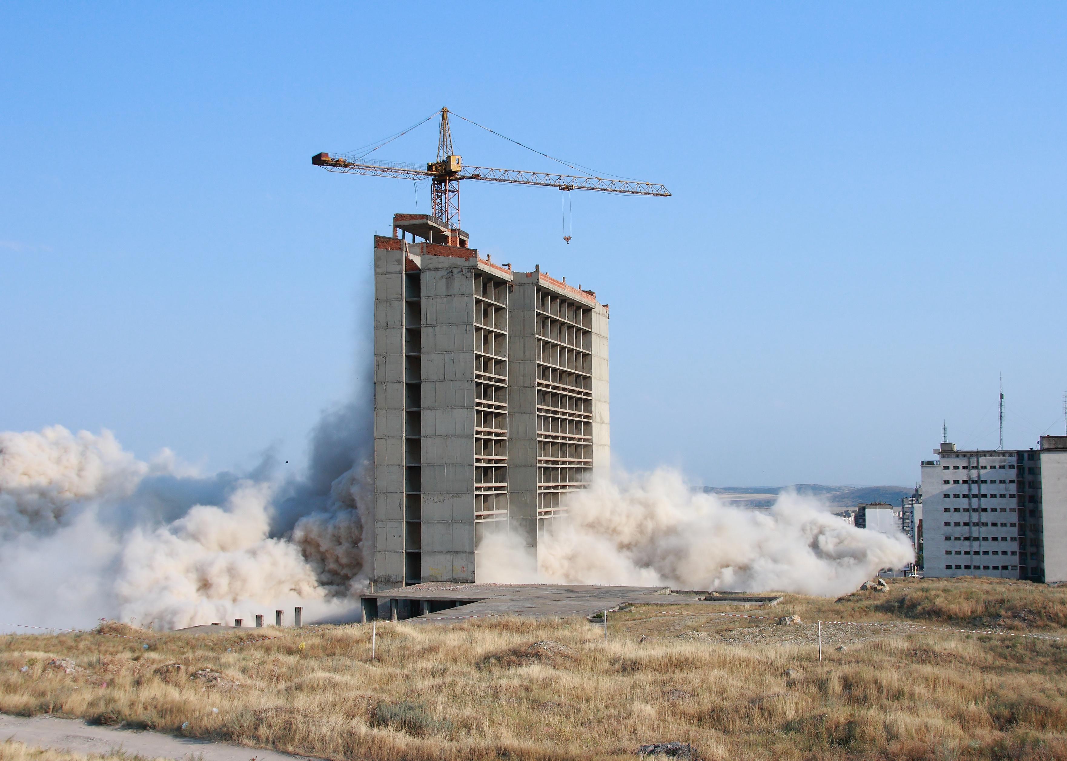 Part of a building is imploded by explosives.