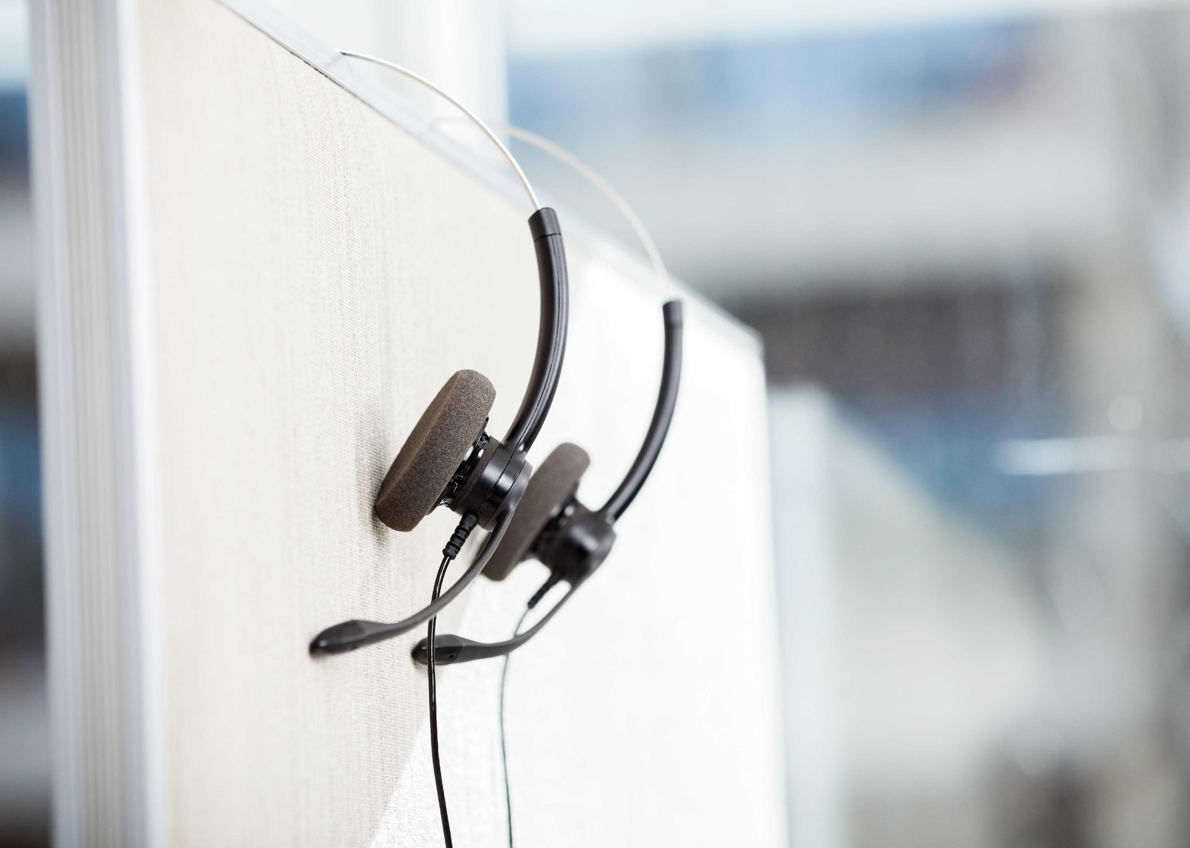 Headphones hanging on cubicle partition in empty office.