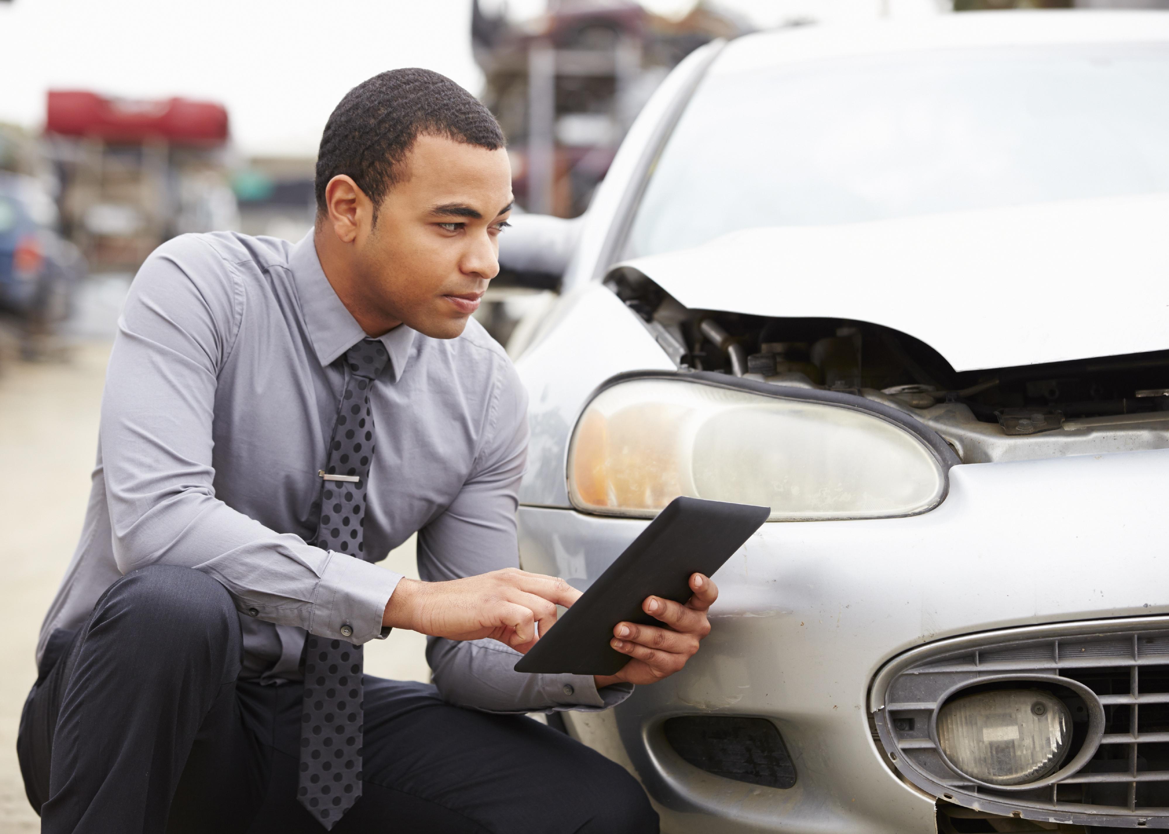 Loss Adjuster Using Digital Tablet In Car Wreck Inspection