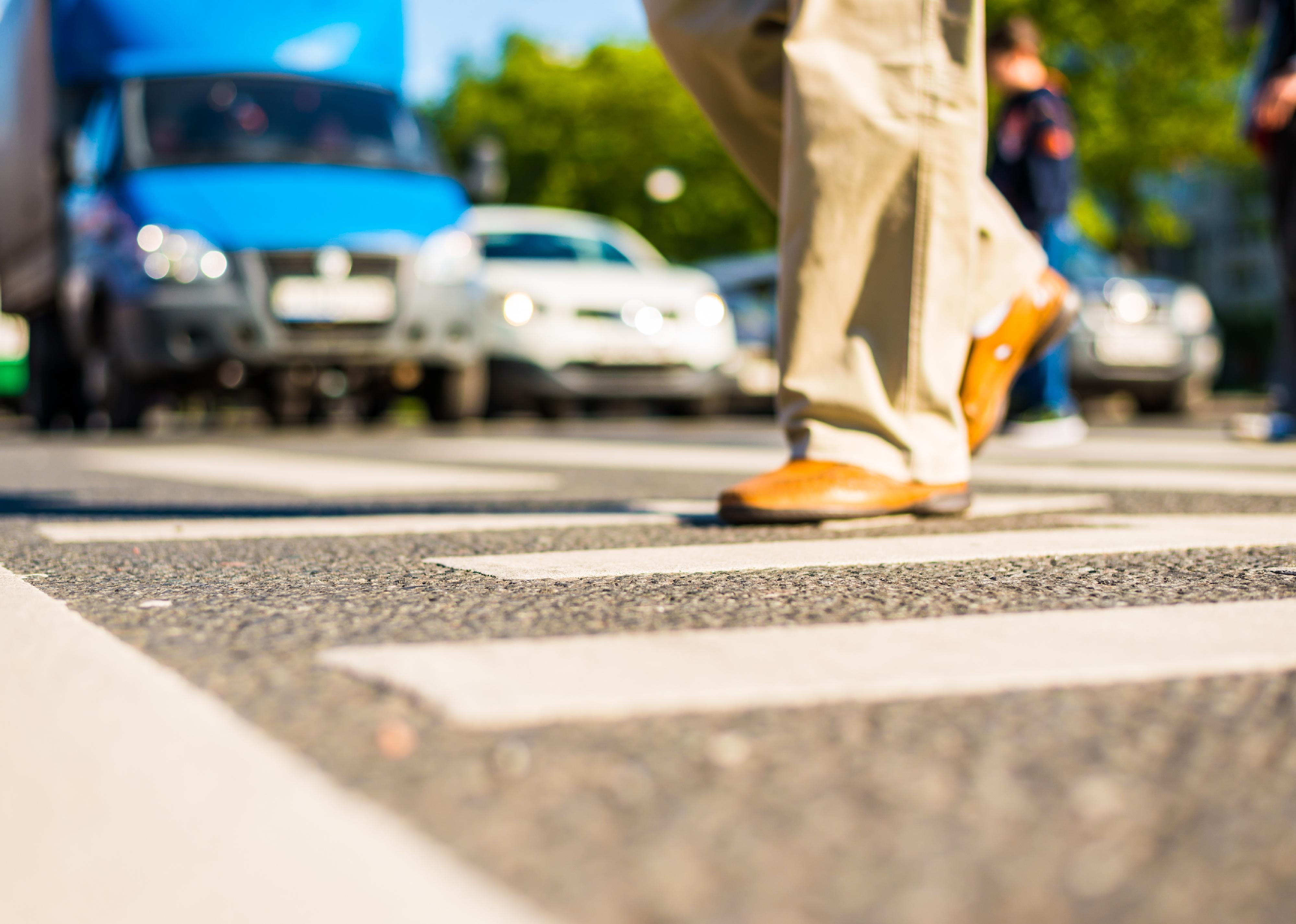 Sunny day in a city with pedestrians crossing a road