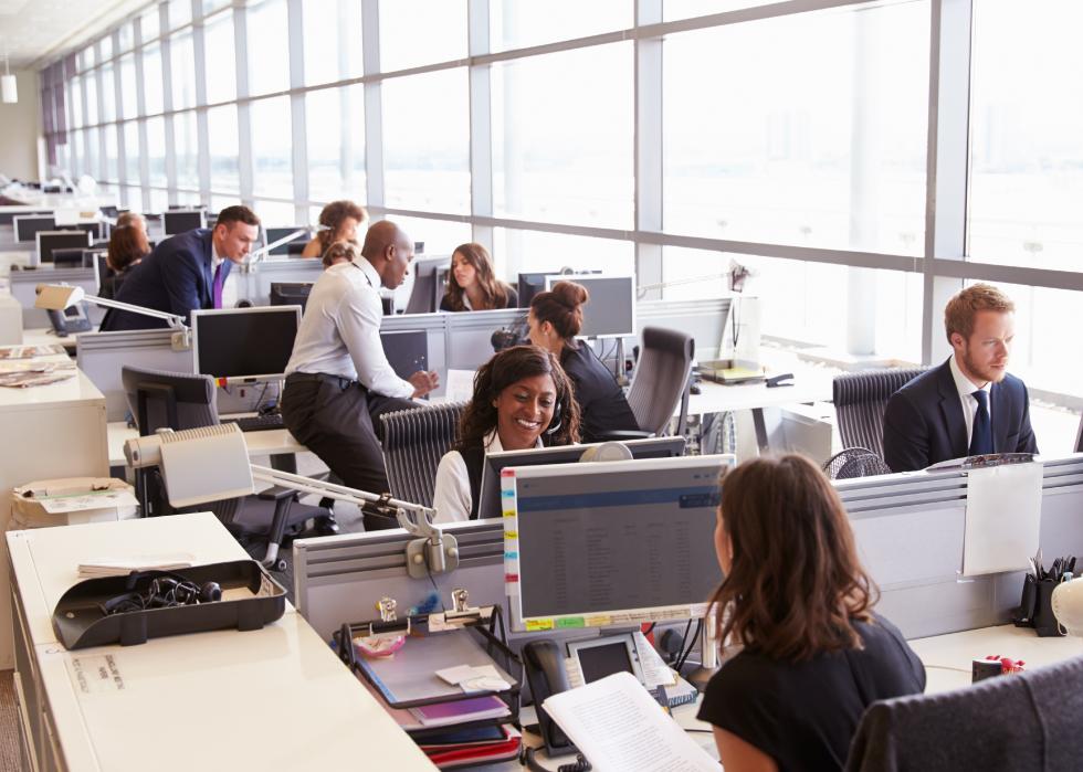 Coworkers at their desks in a busy, open plan office