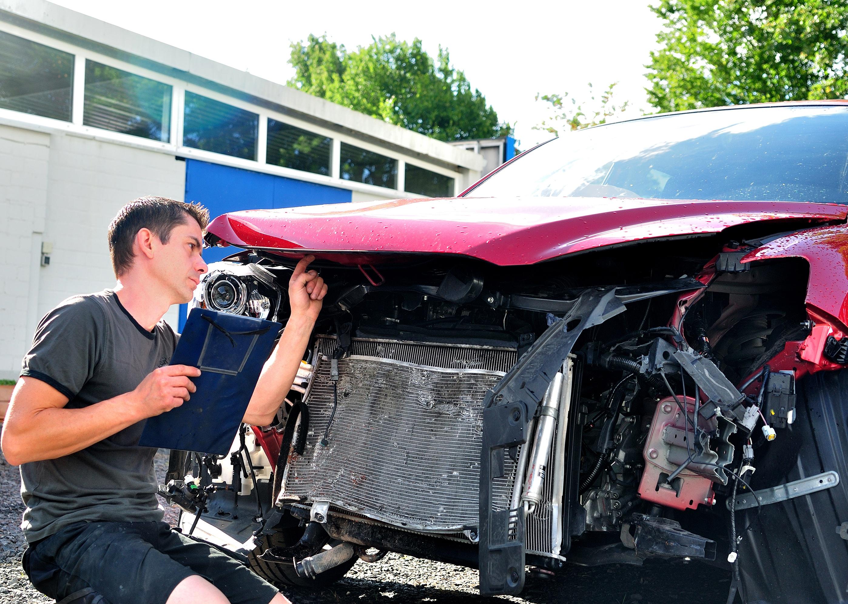 Man inspecting car damage after crash