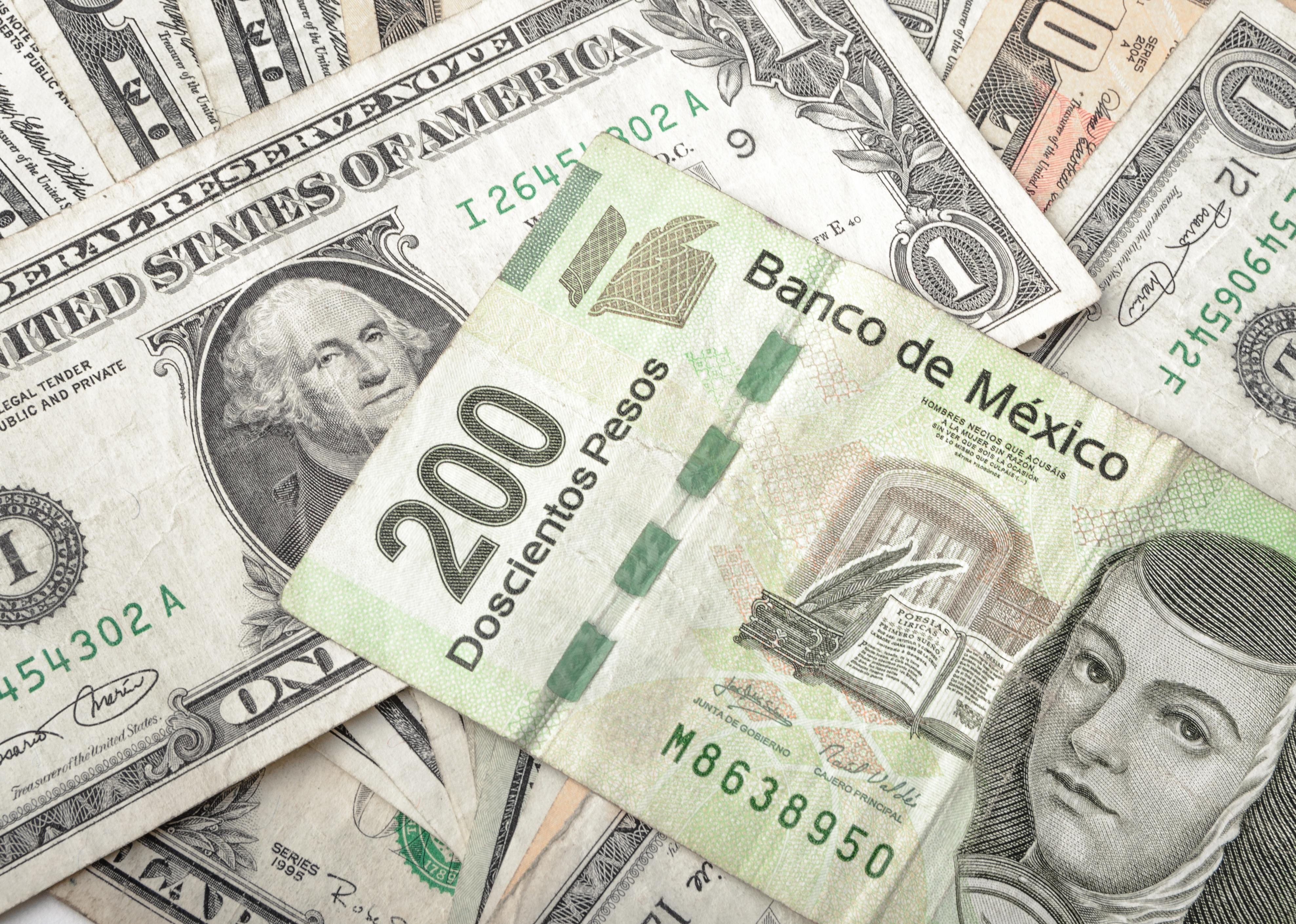 Dollars and Mexican Pesos assorted bills cash pile.