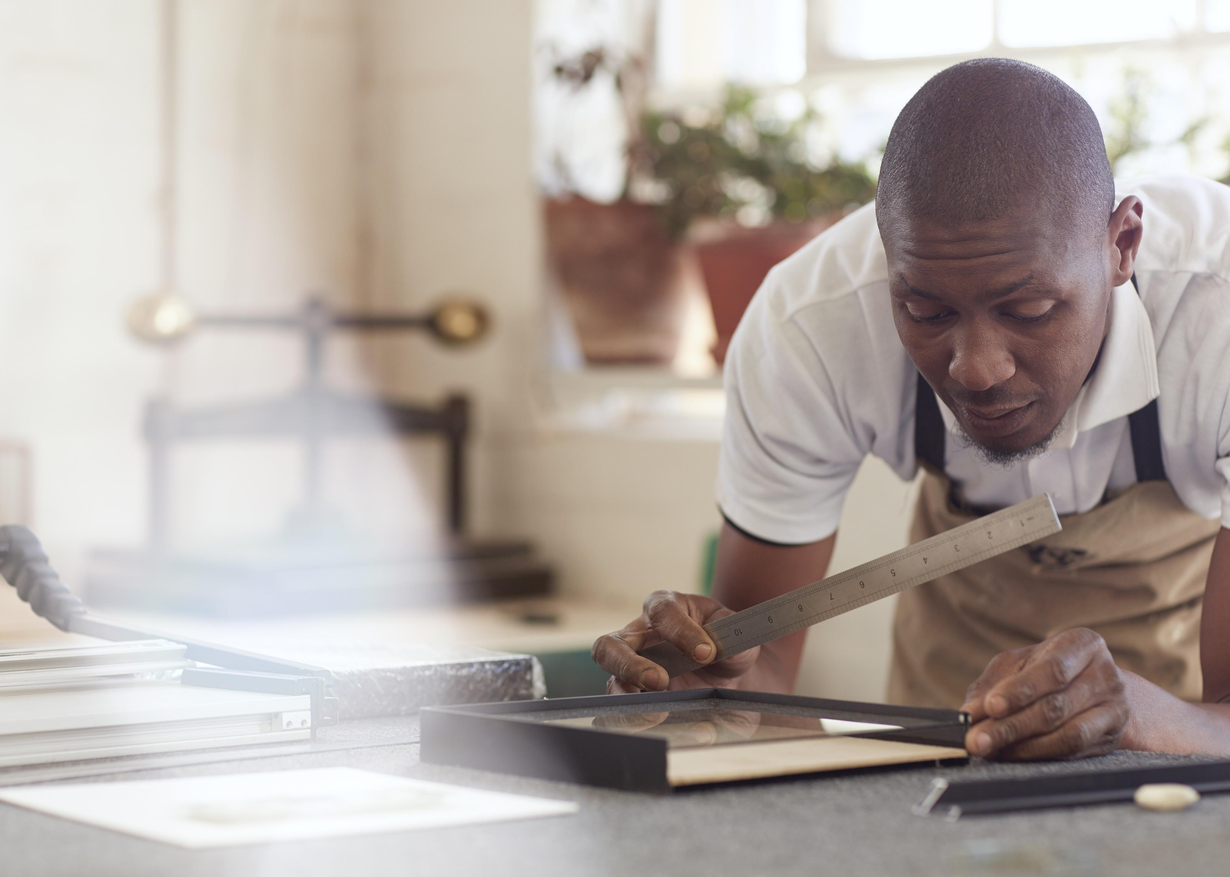 A carpenter taking measurements for a frame.