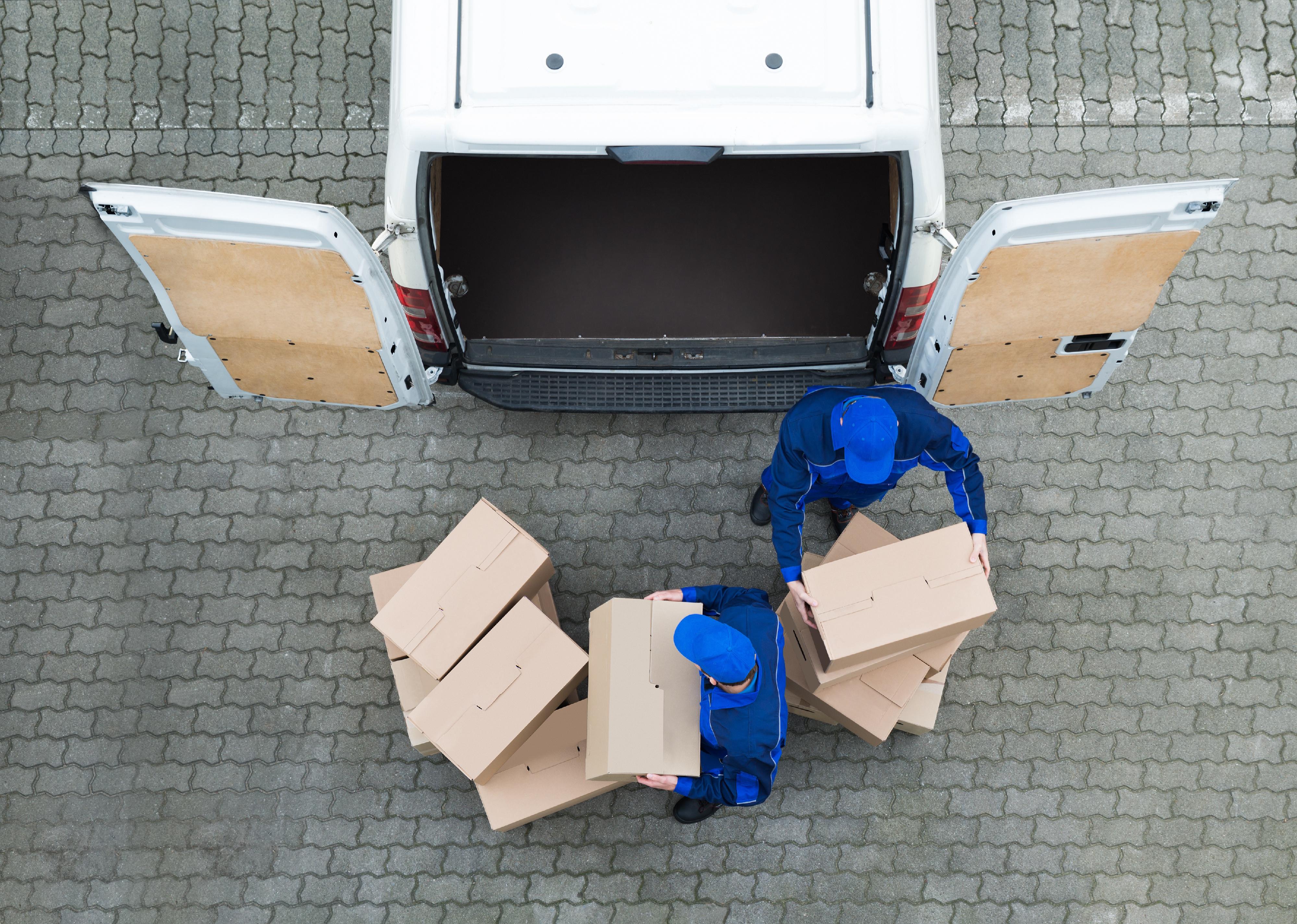 Aerial shot of delivery men unloading cardboard boxes from truck on street.