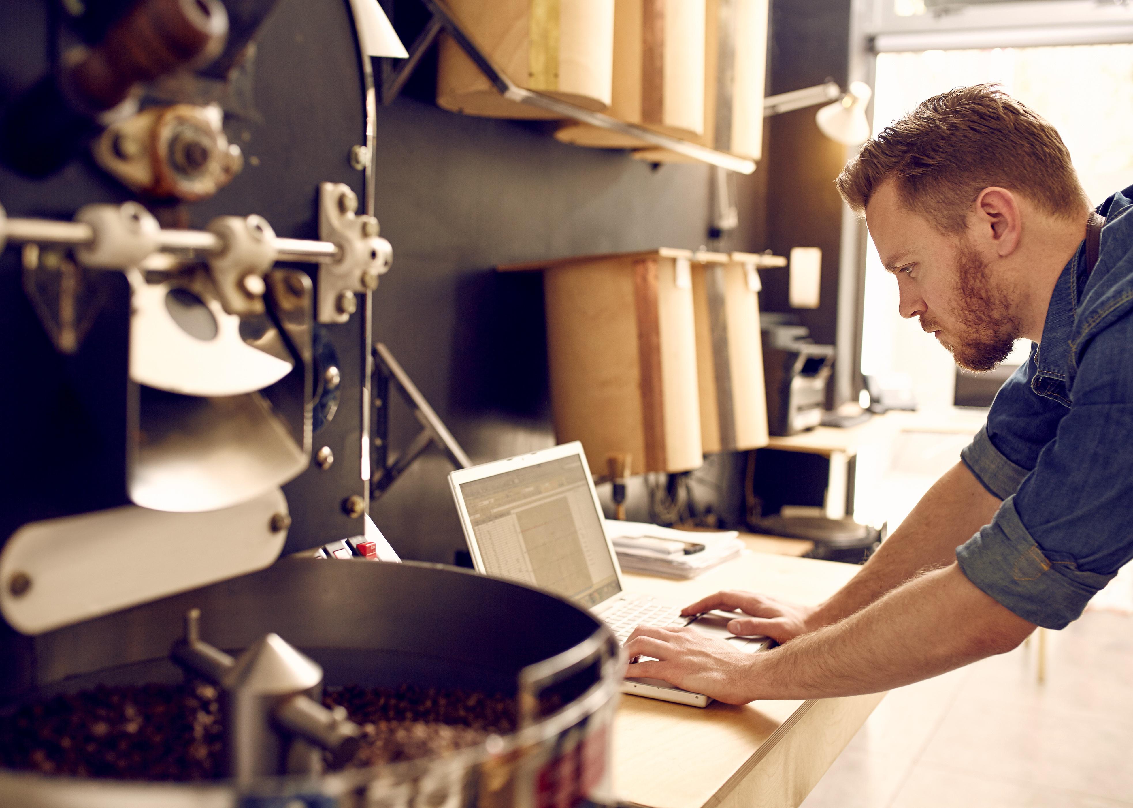 Business owner of a coffee roastery checking his laptop.