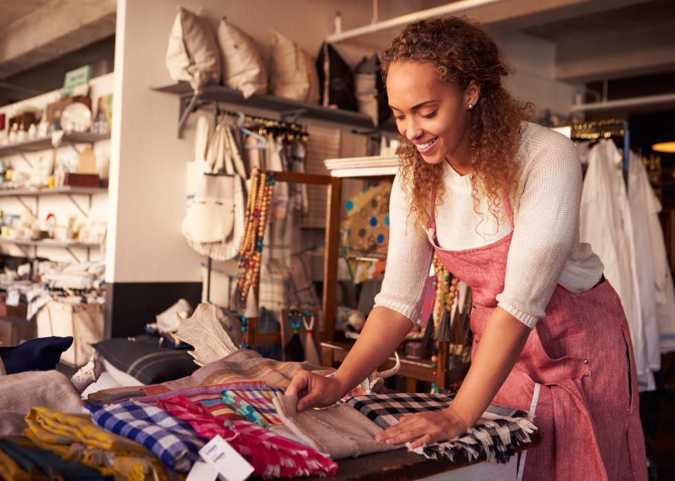 Female arranging textiles In homeware store