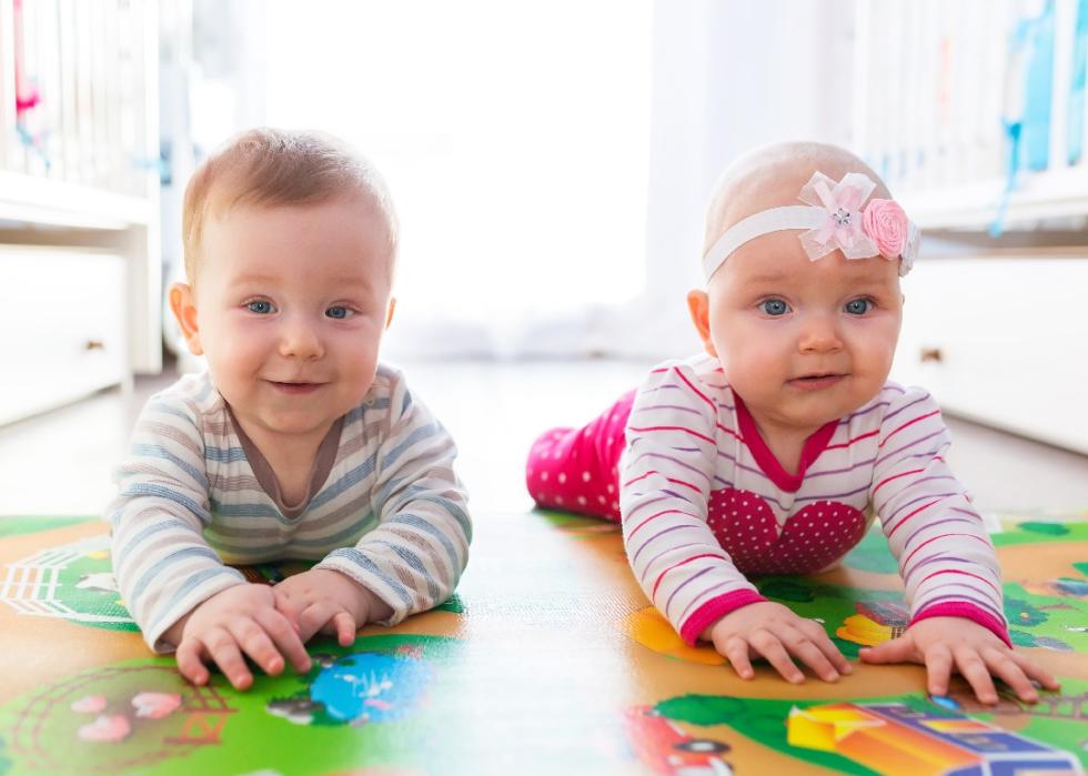 Twin baby boy and girl playing with a ball at home.
