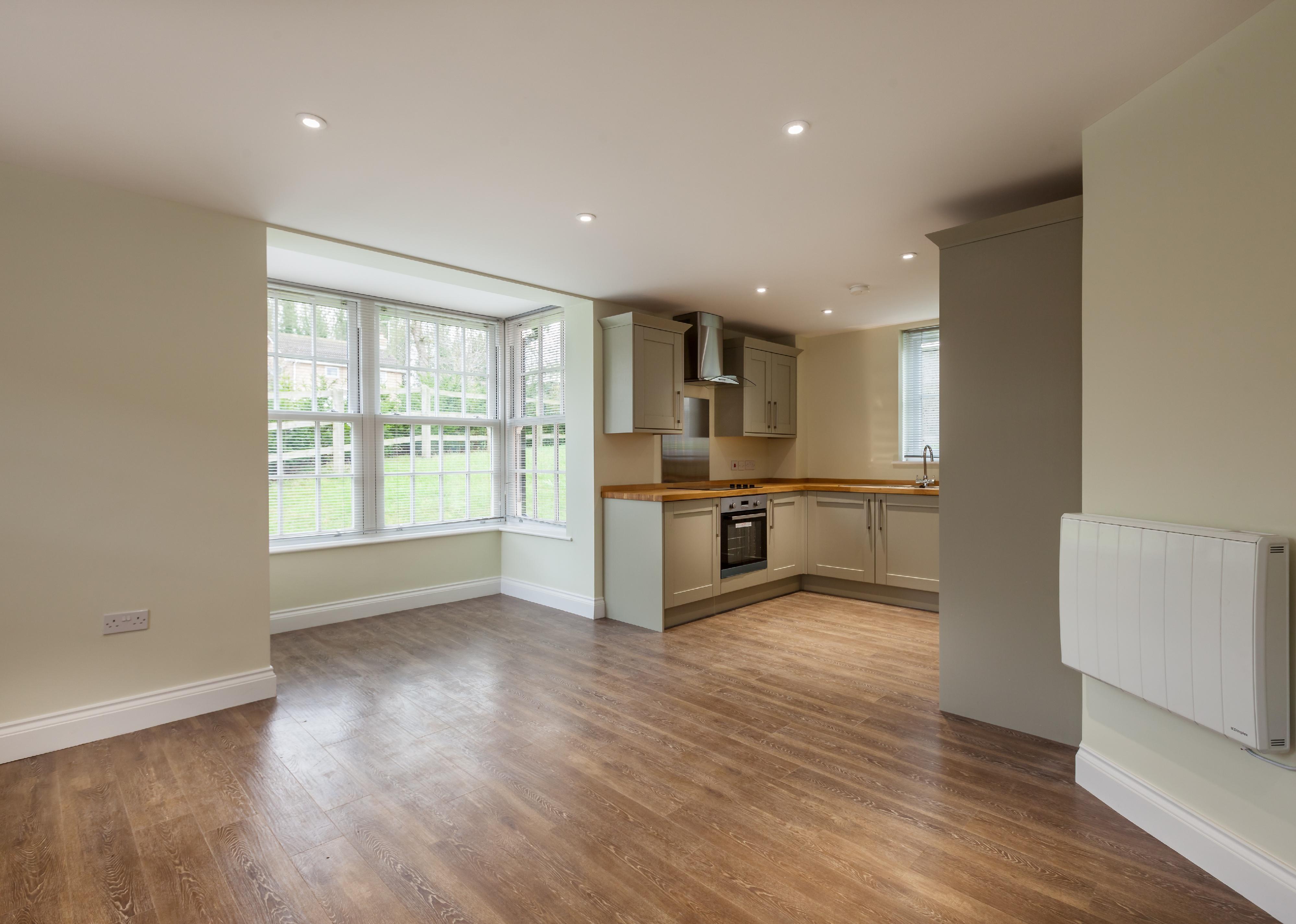 Empty home with dining area and kitchen in back.