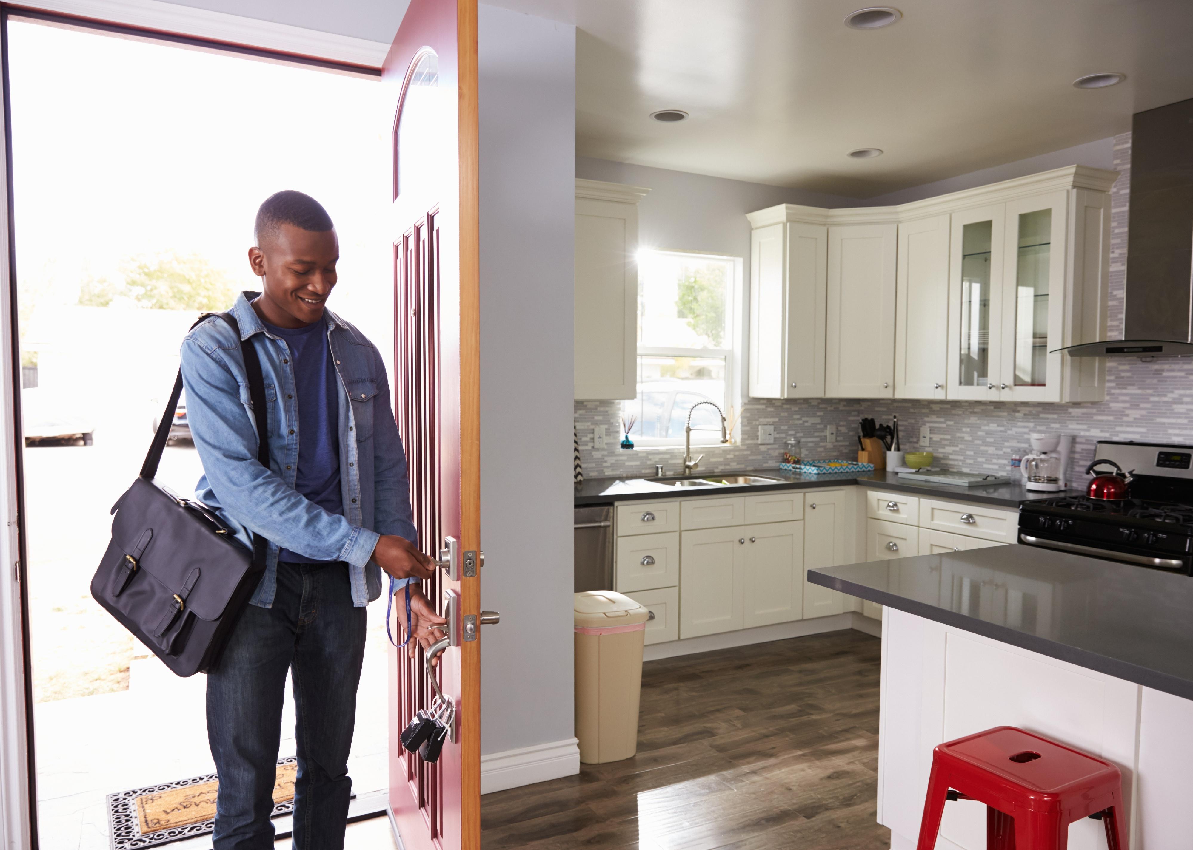 Man coming home and opening front door of apartment.