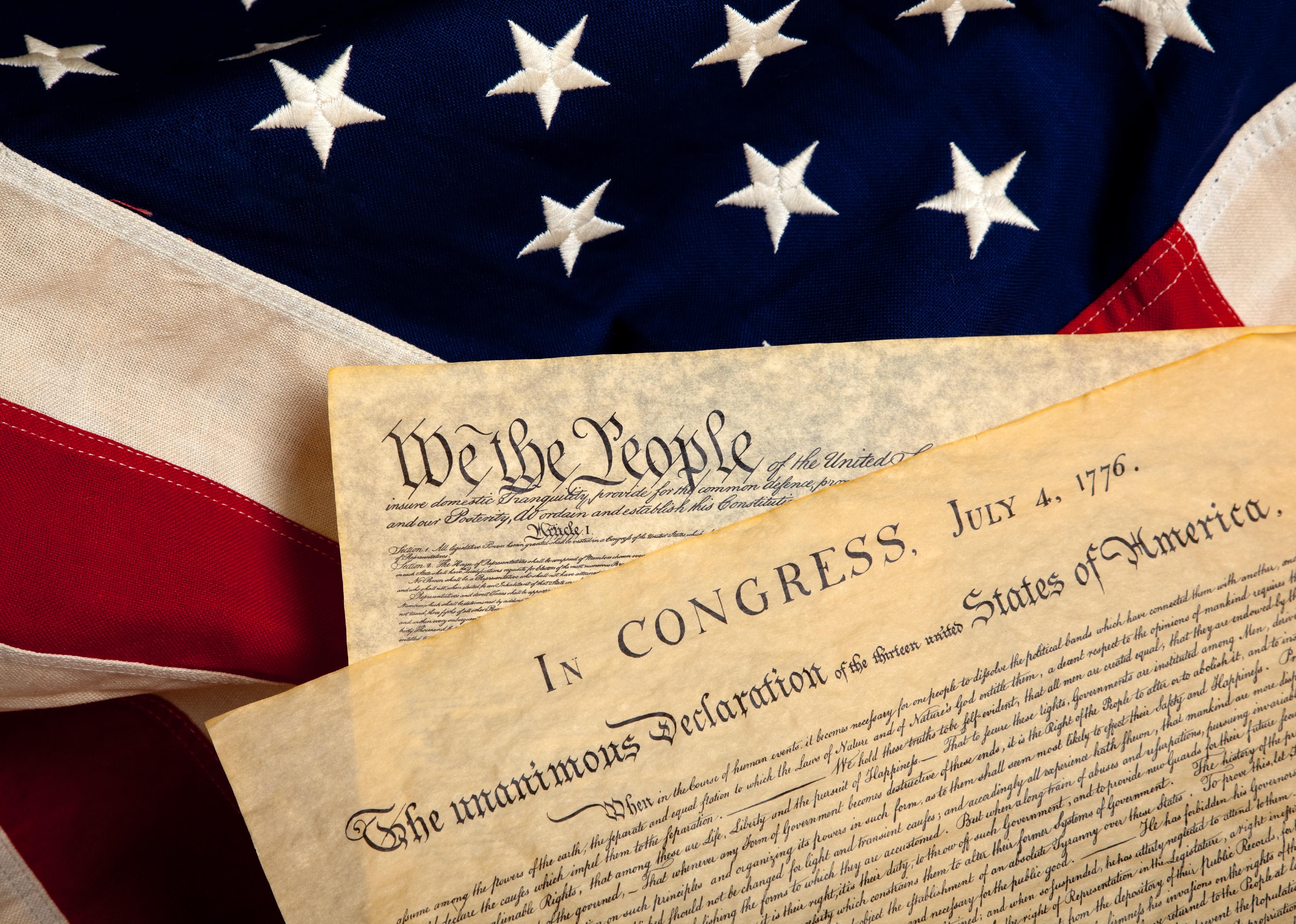 United States' Constitution and Declaration of Independence on a flag background