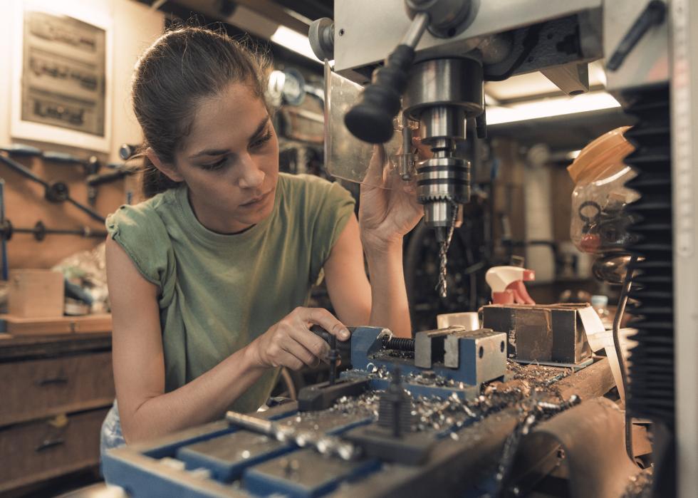 Female mechanic using a vertical electric drill machine
