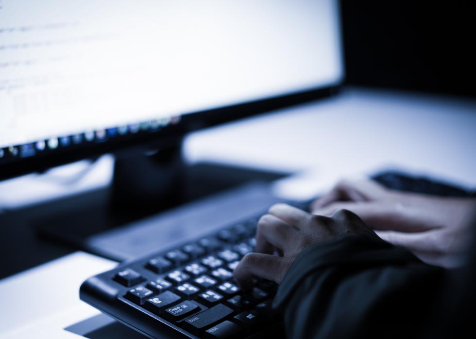 Unseen computer hacker stealing information with laptop.