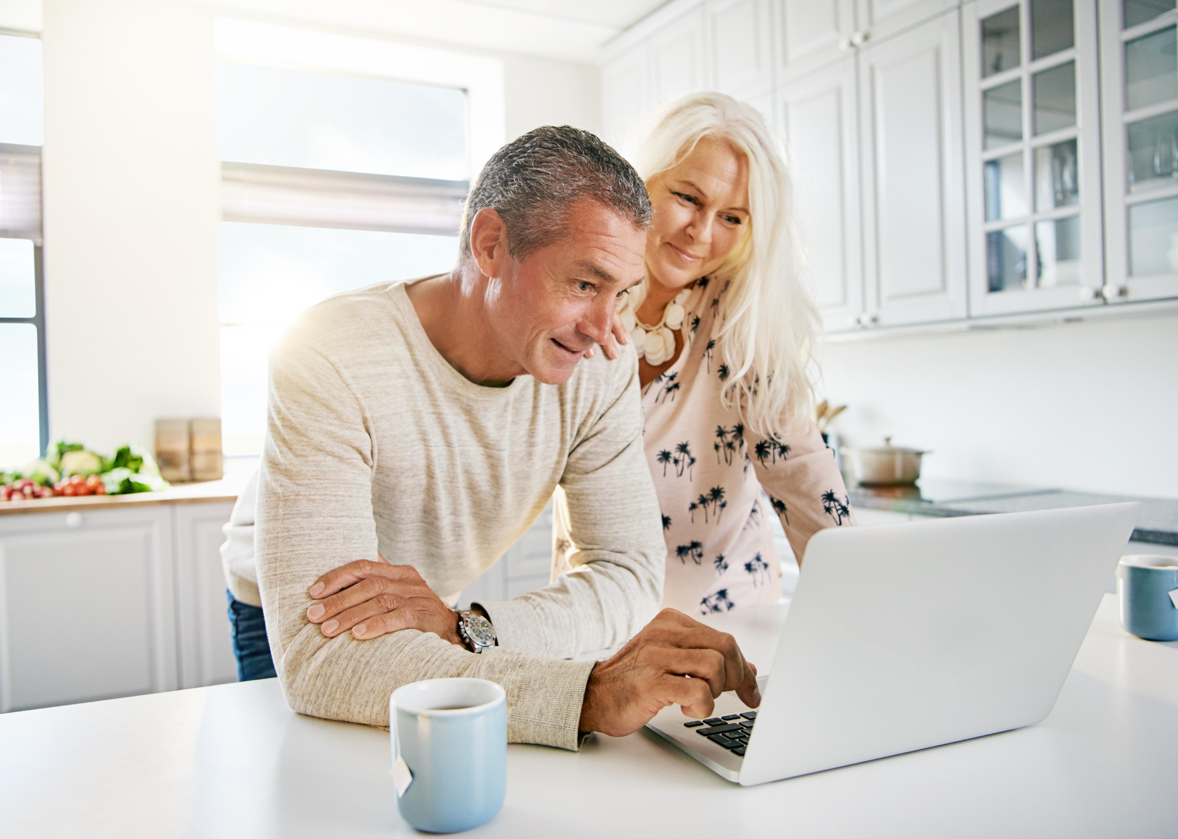 Elderly couple reading on a laptop computer.