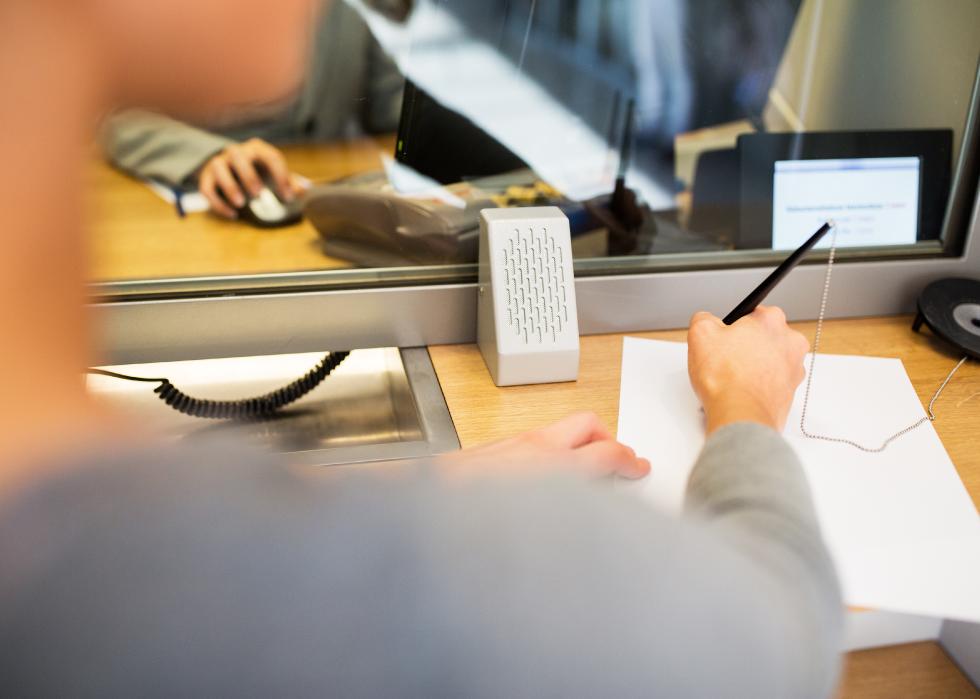Customer with pen and paper at bank office.