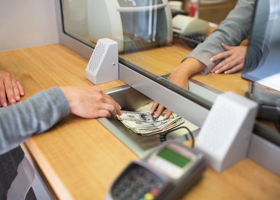 Clerk giving cash to customer at bank office.