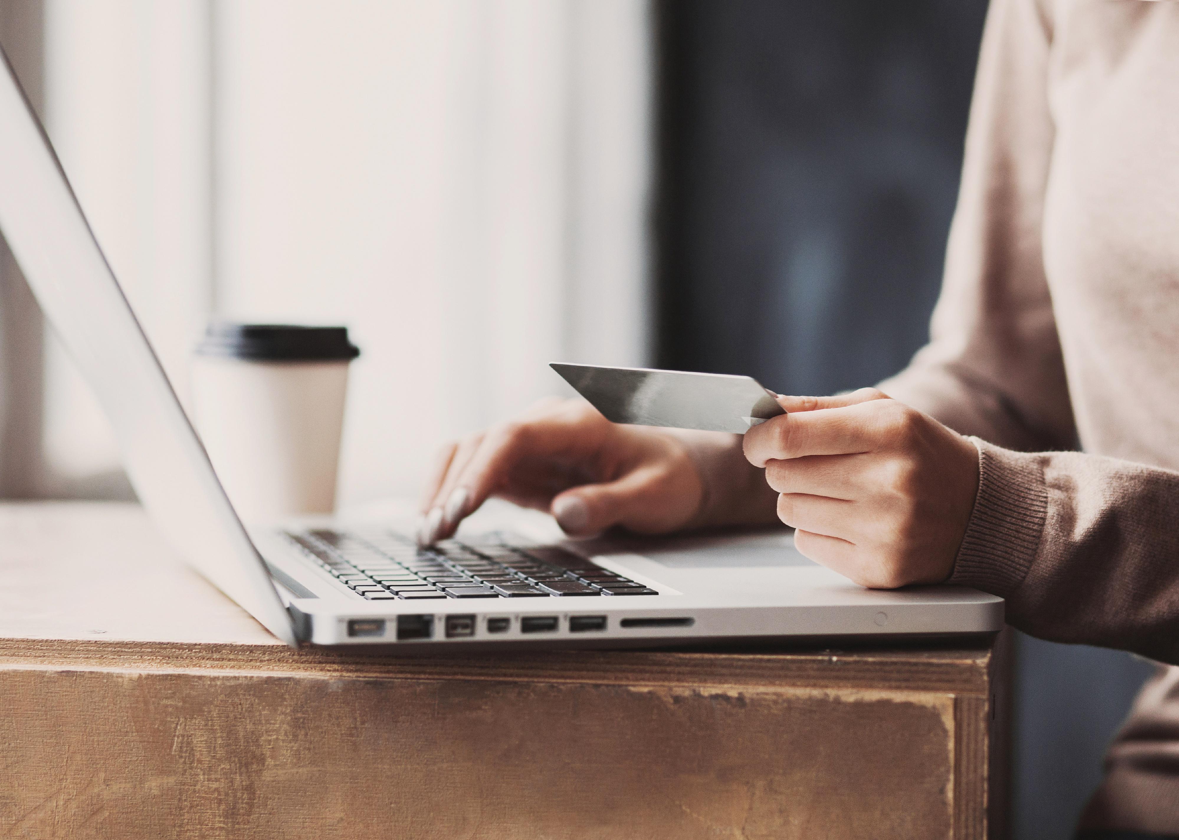 Woman hand holding credit card and using laptop.