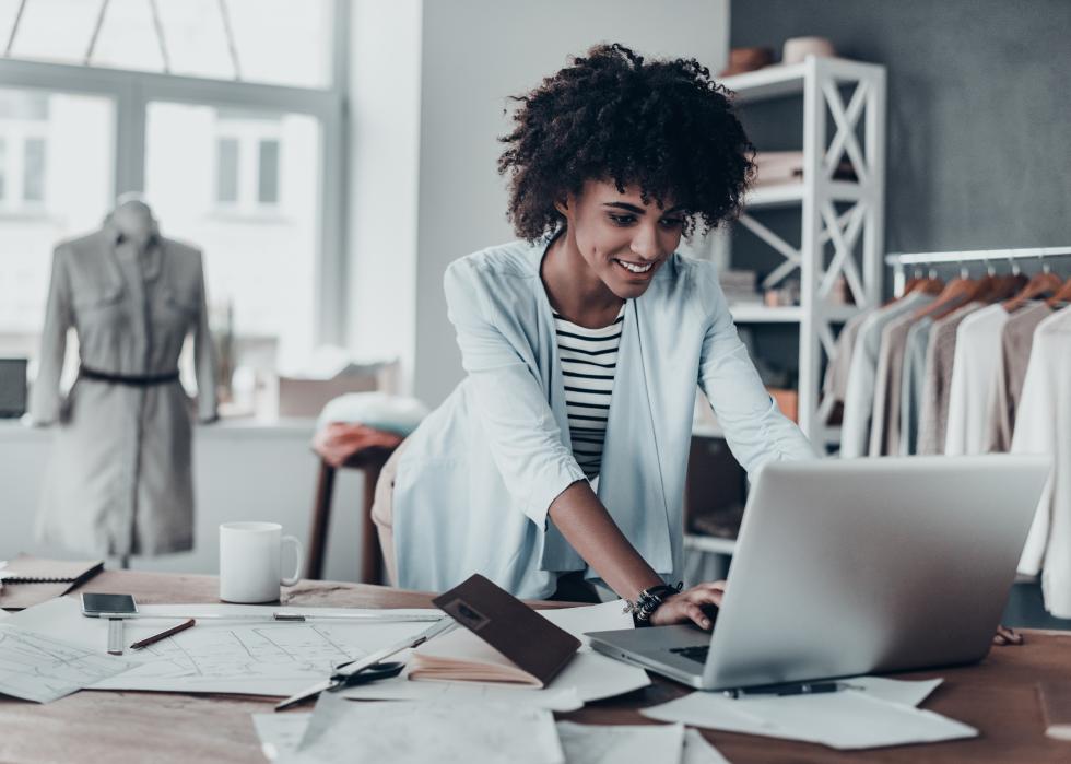 Young African woman using computer while standing in workshop