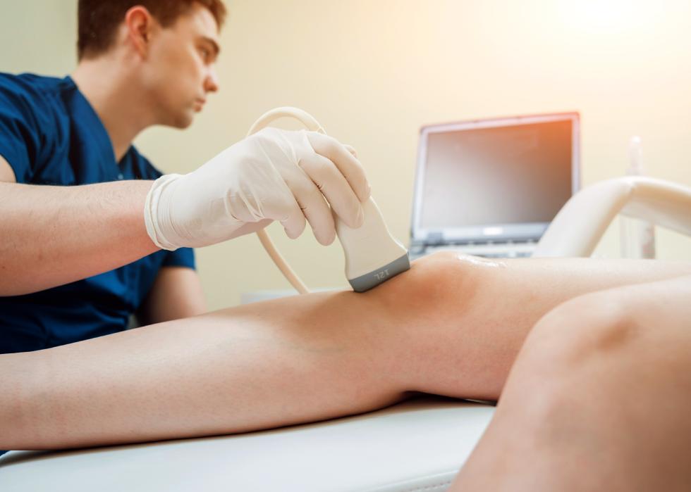 Patient with doctor doing a sonography on his knee.