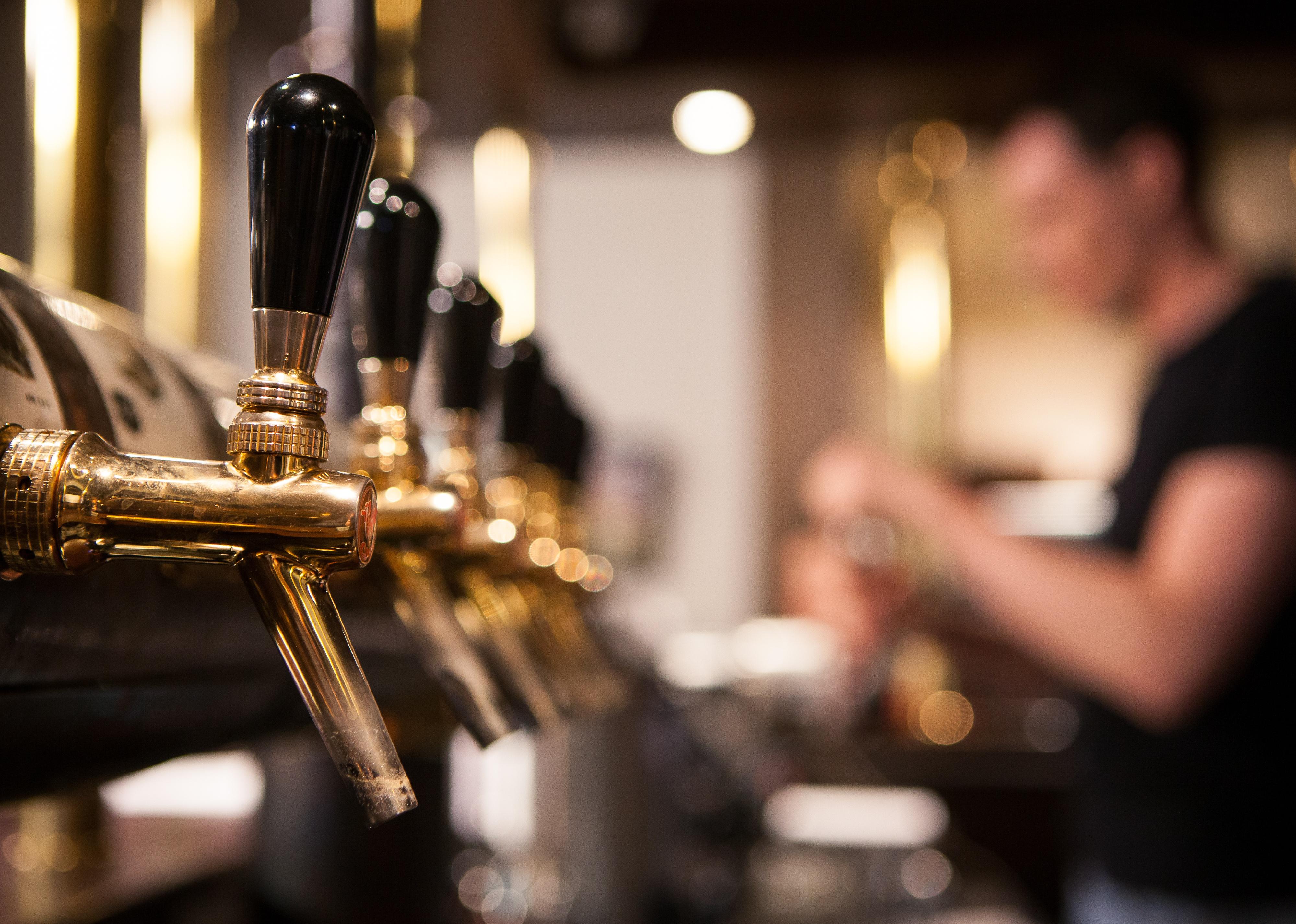 Beer taps in the bar with the bartender in the background
