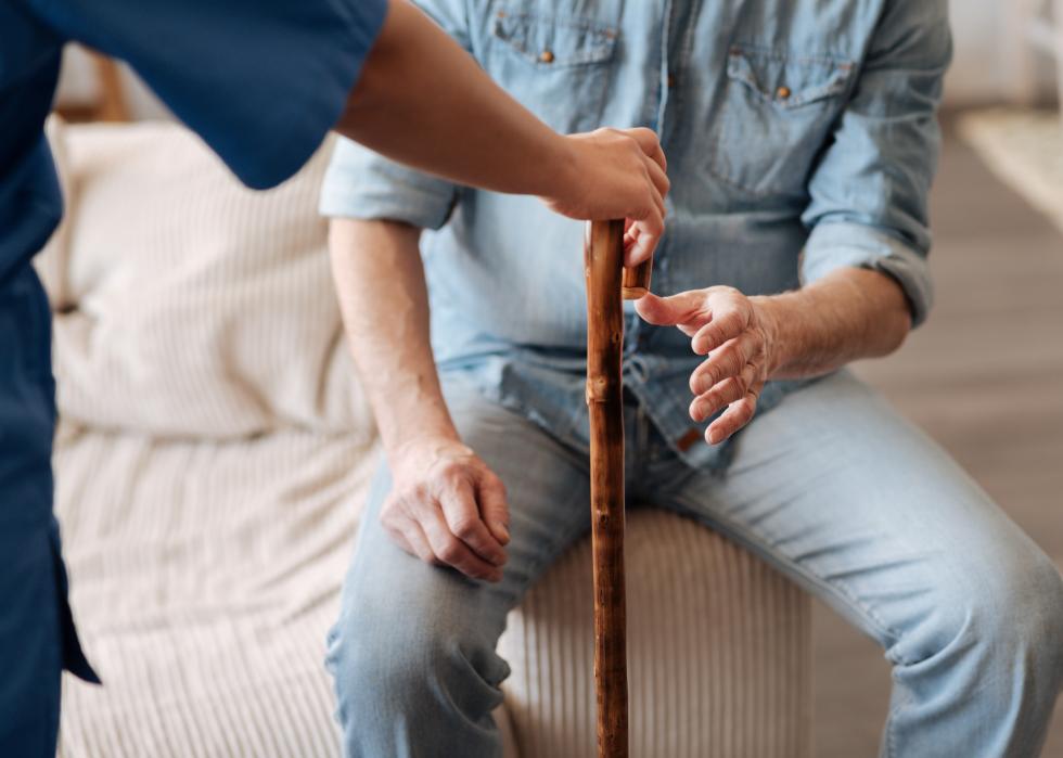Nurse handing over a walking cane to a patient.