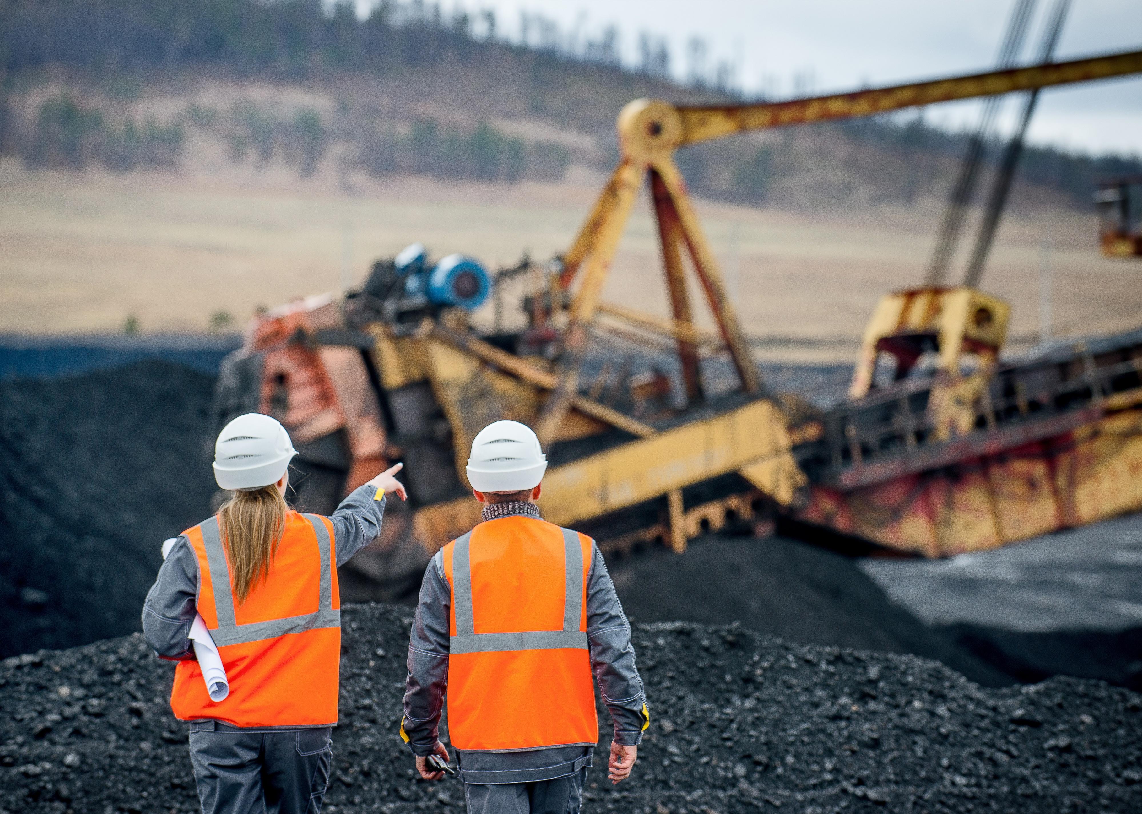 Workers pointing at mining excavating equipment.
