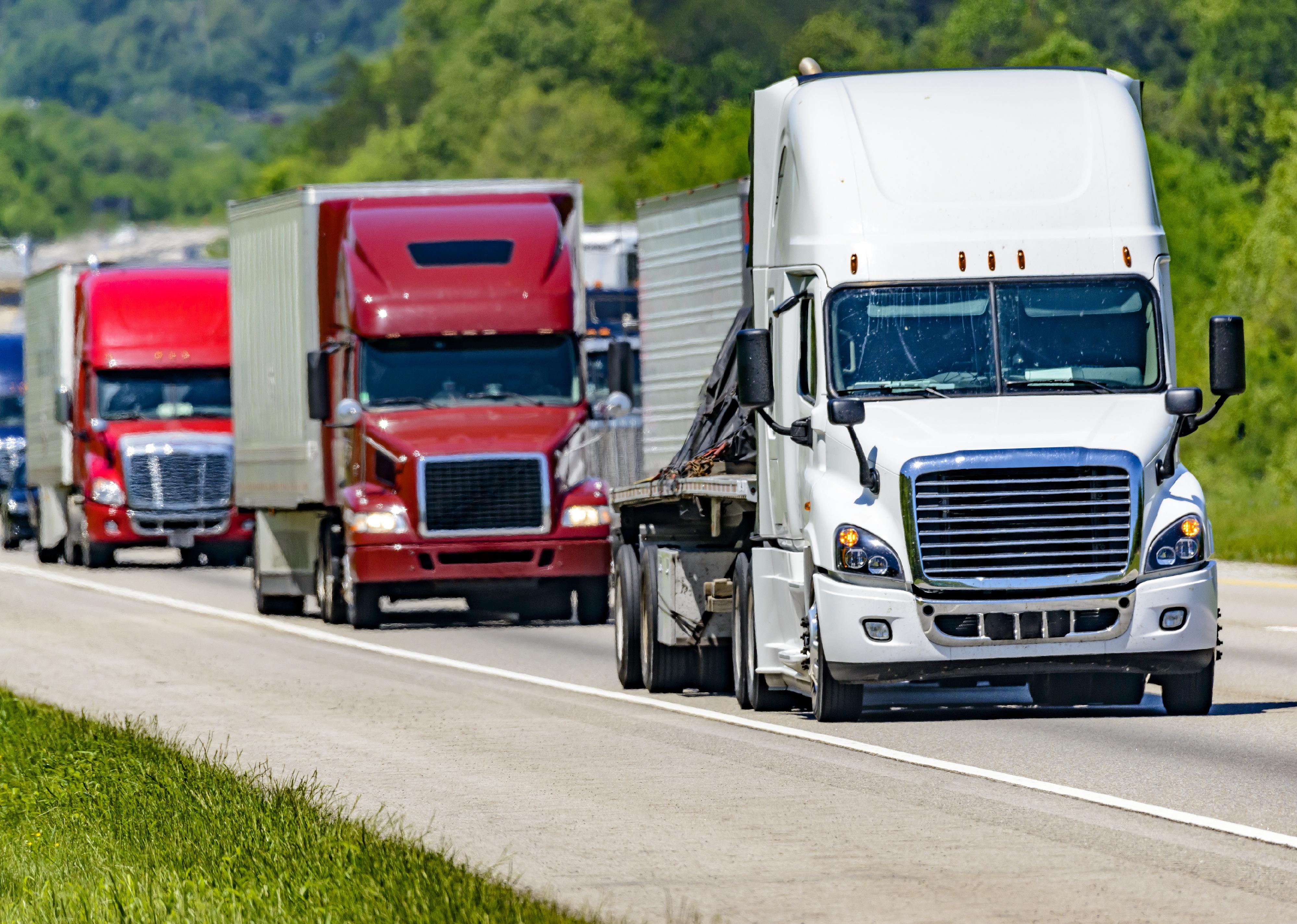 A line of eighteen-wheelers on an interstate highway.