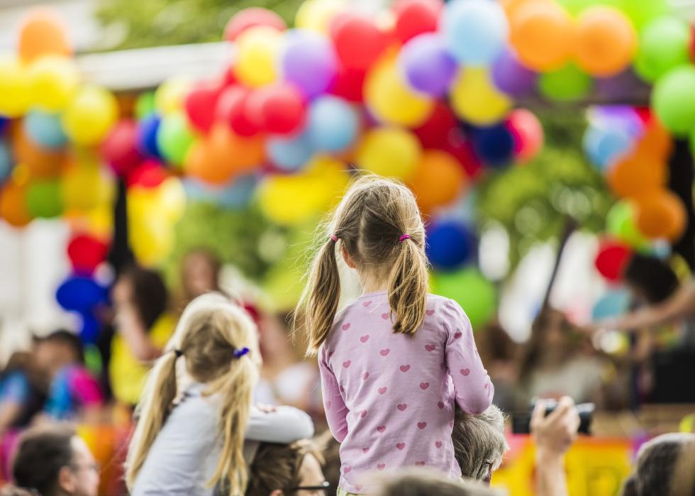 Two little girls watching colorful balloons in parade