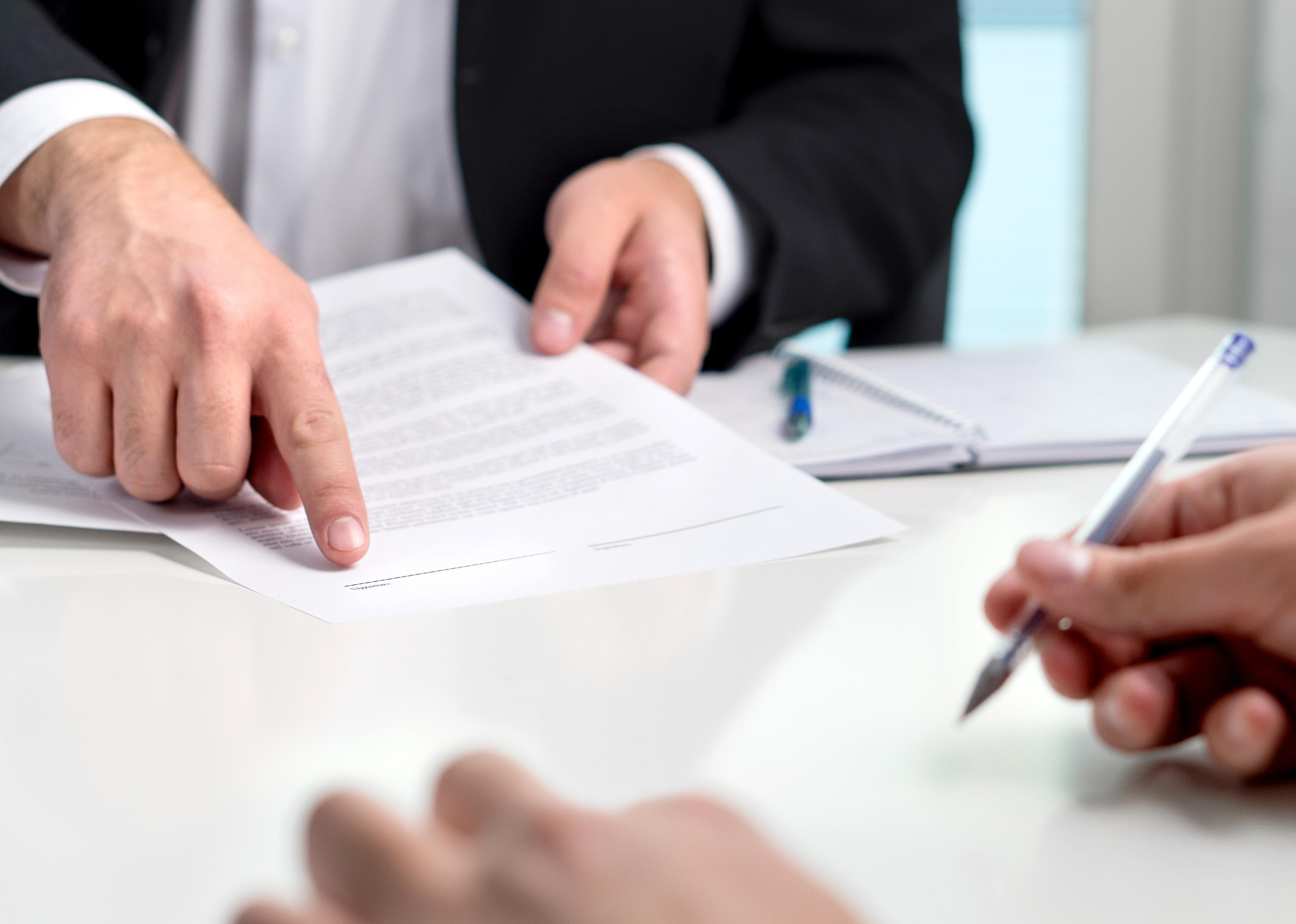 Lawyer pointing client to the line for signature on a document.