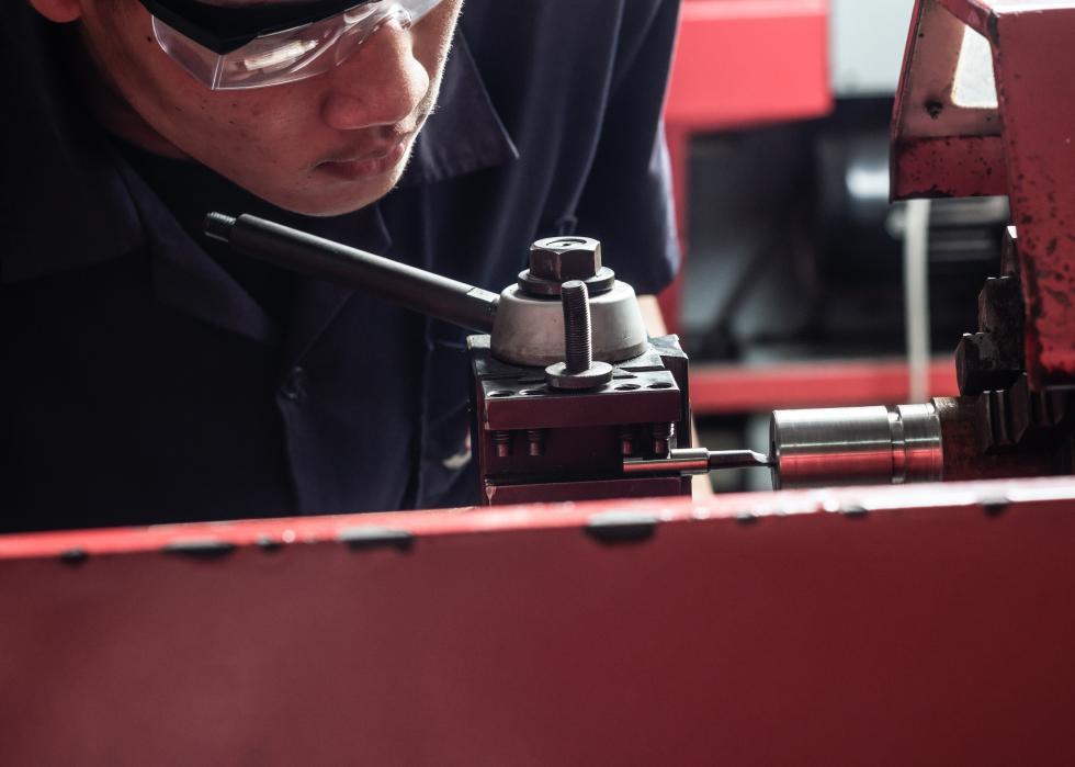 Close up of technician turning horizontal lathe machine