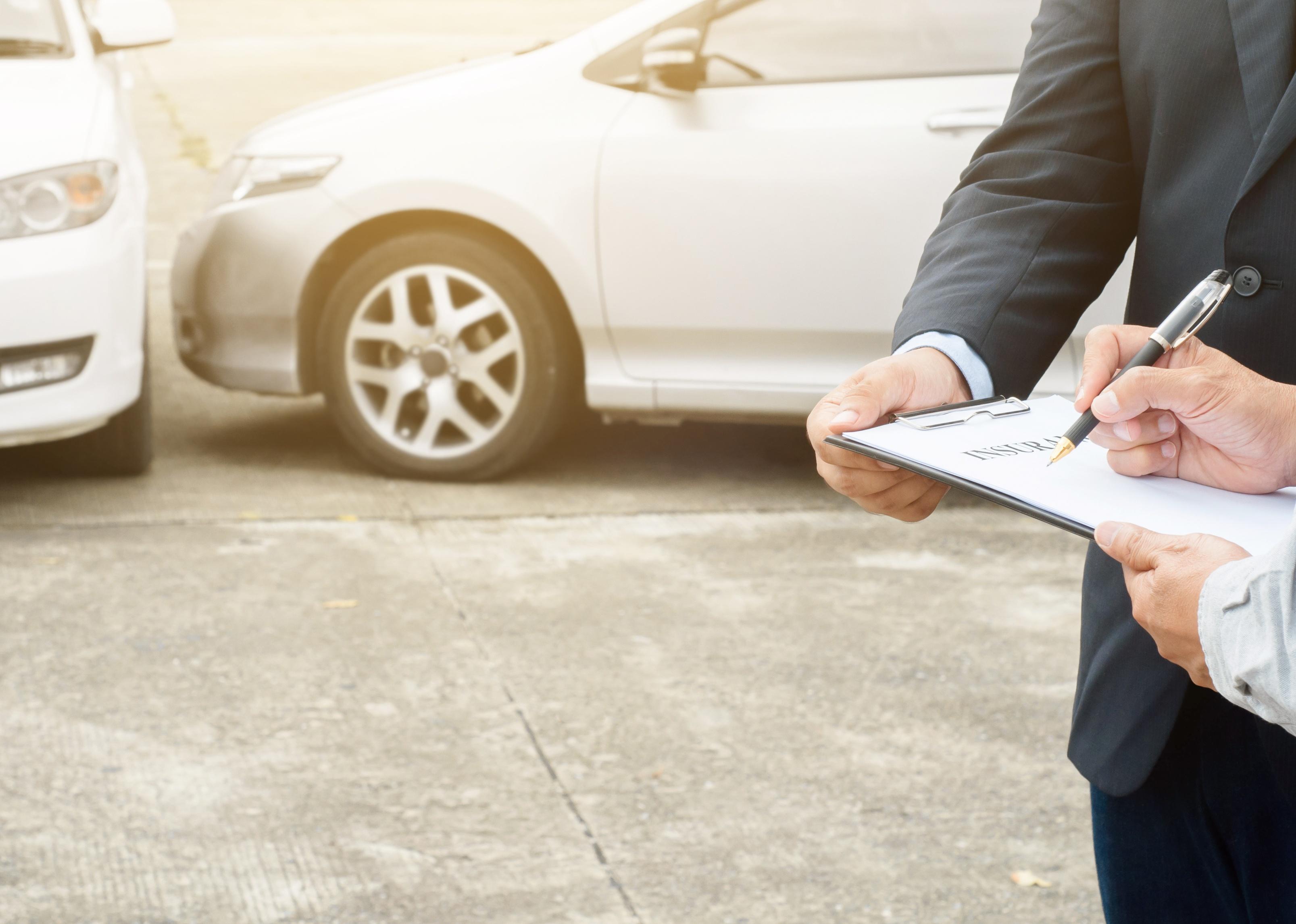 Man and insurance agent look at paperwork after car crash