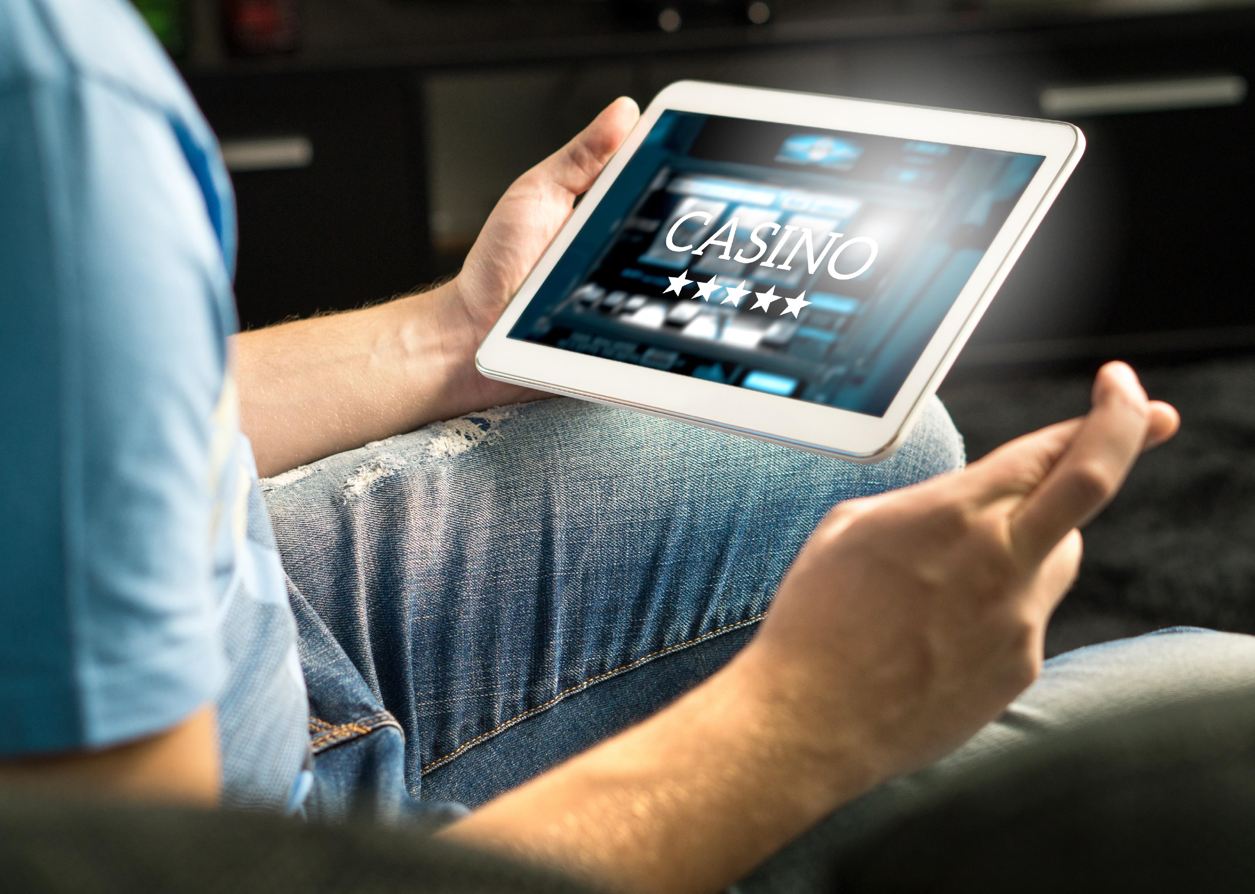 Man playing in an online casino with tablet, fingers crossed.