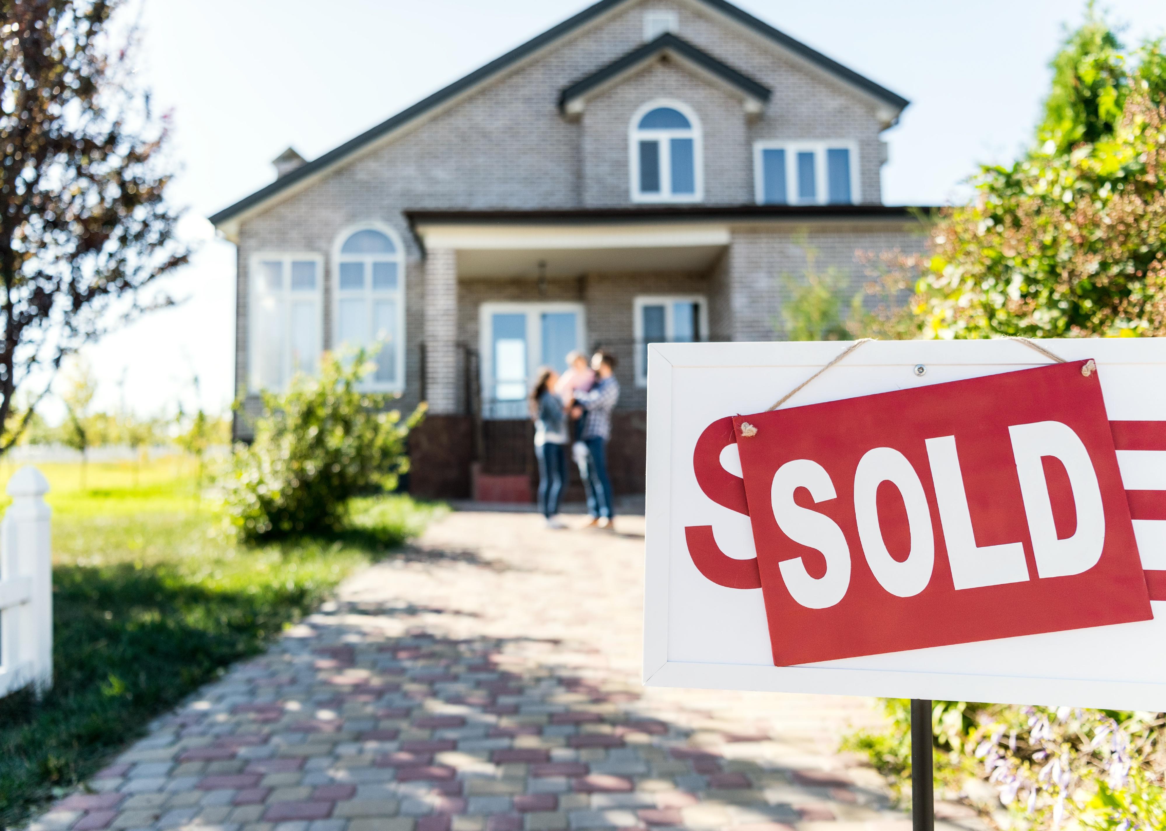 Sold house with blurred family on background.