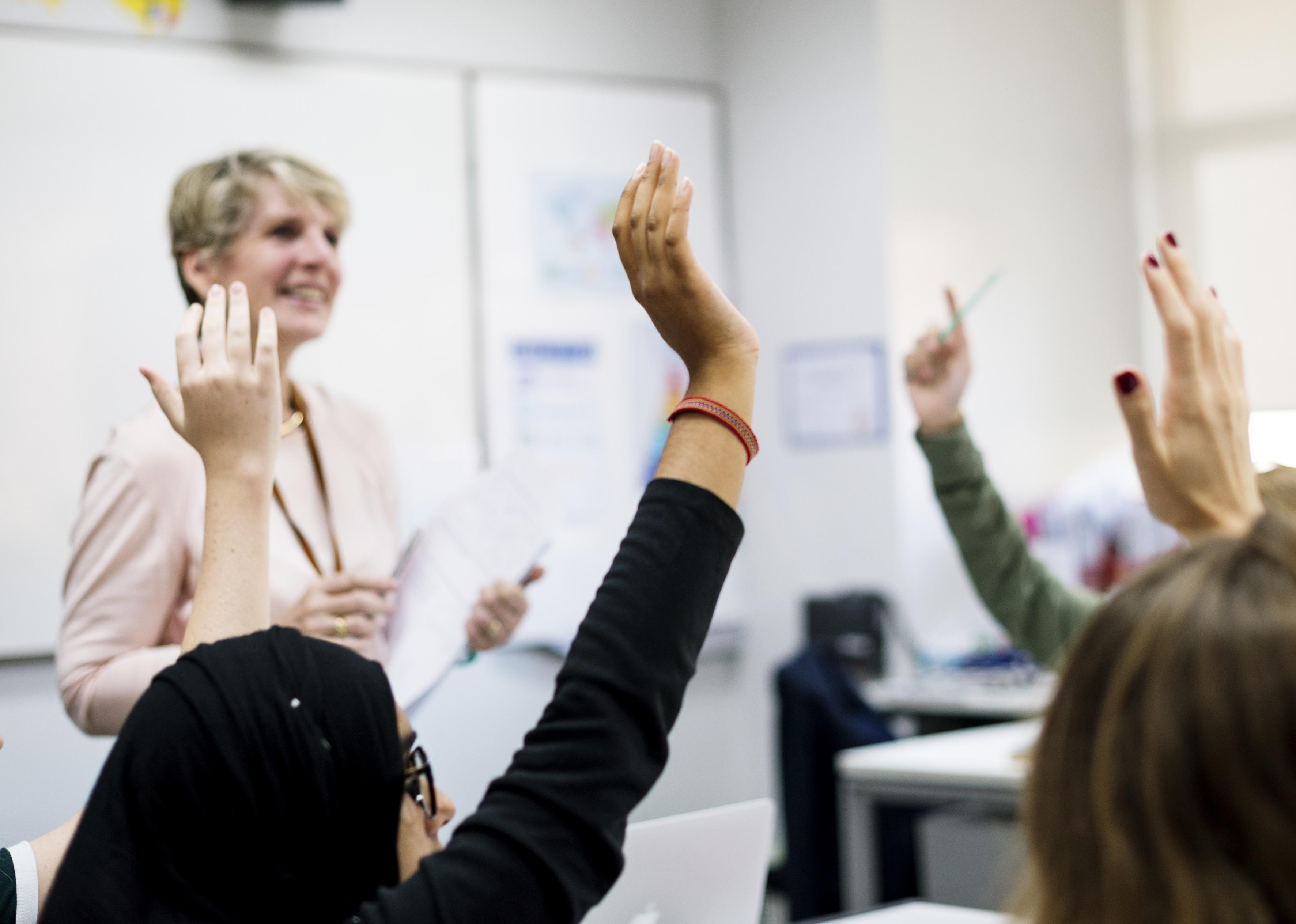 Students with their hands up responding to their teacher