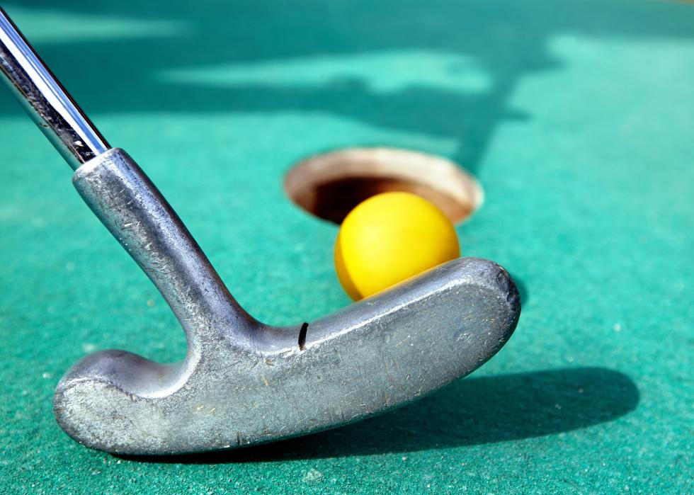 Golf stick and yellow ball on green grass