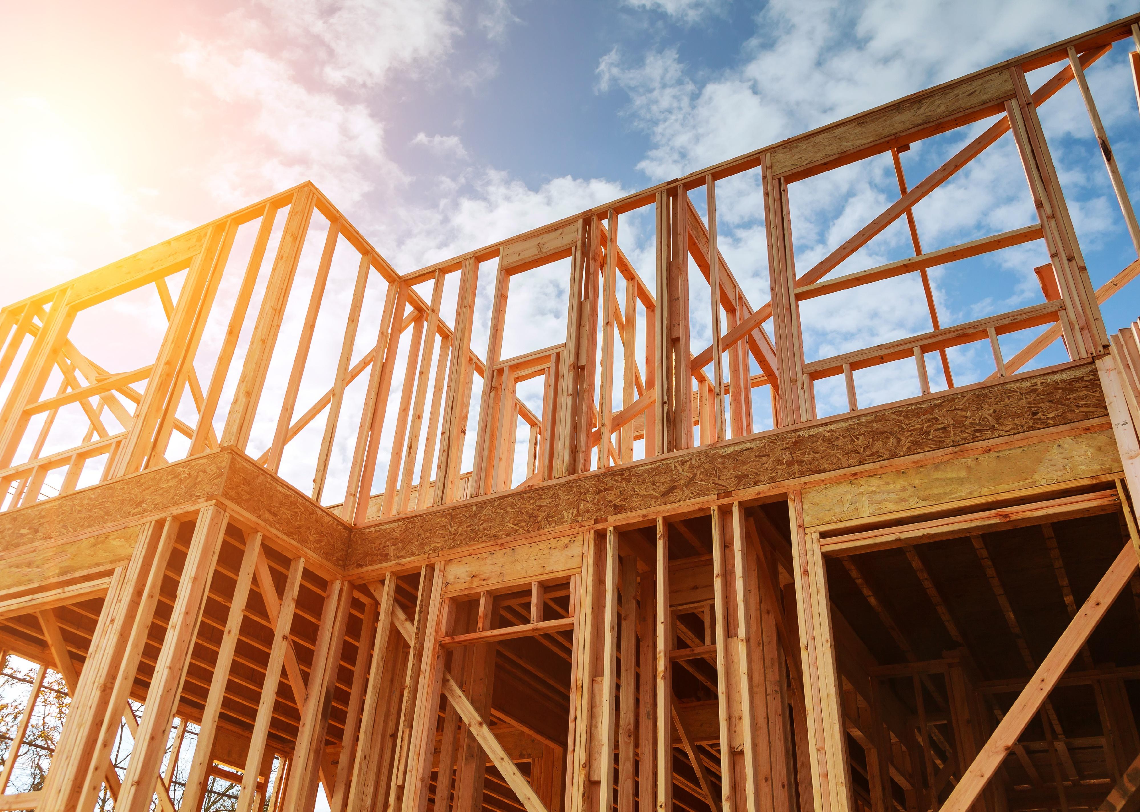 New residential construction home framing against a blue sky.