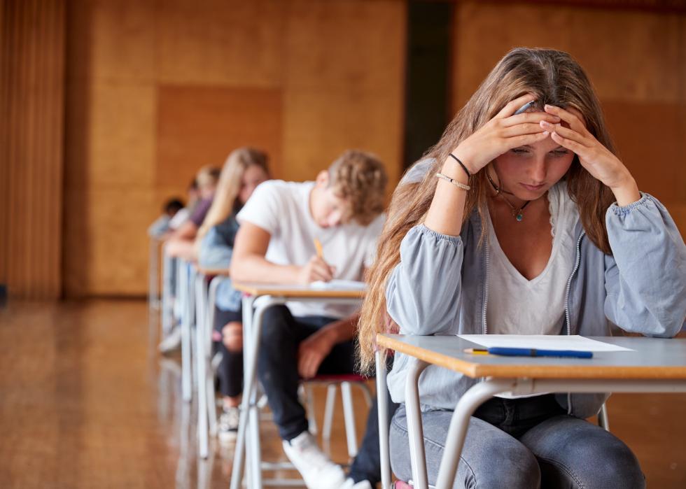 Teens sitting at desks in a row.