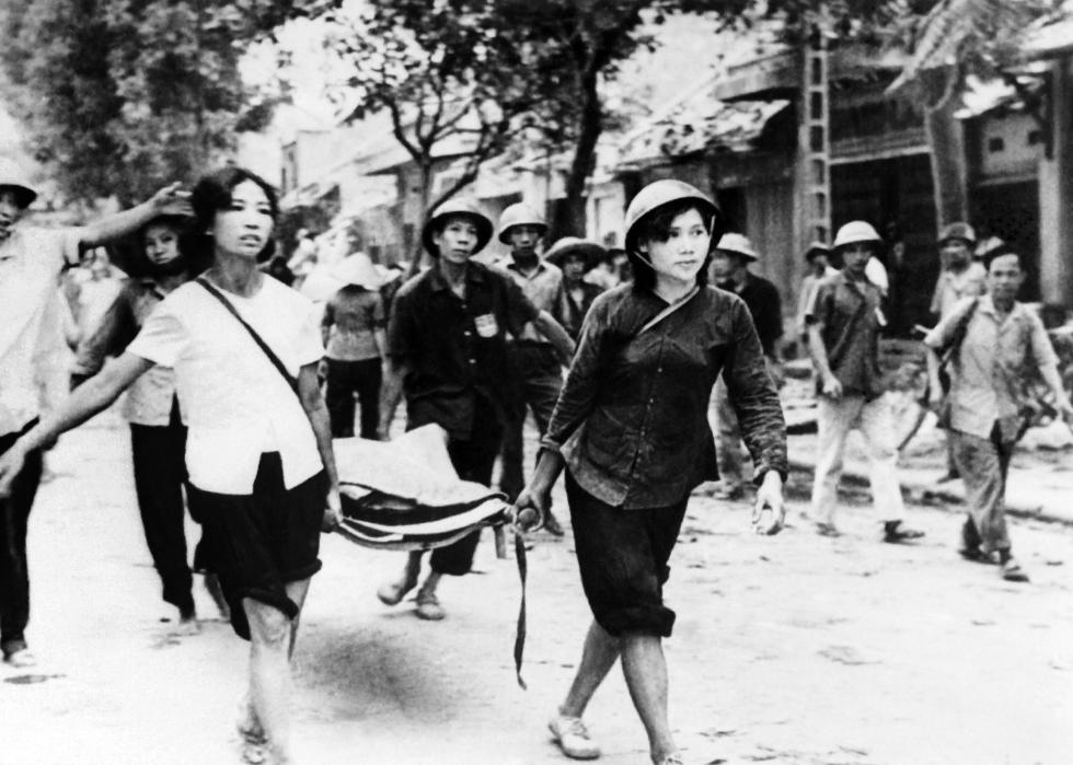 People walk in the street in Hanoi carrying stretcher.