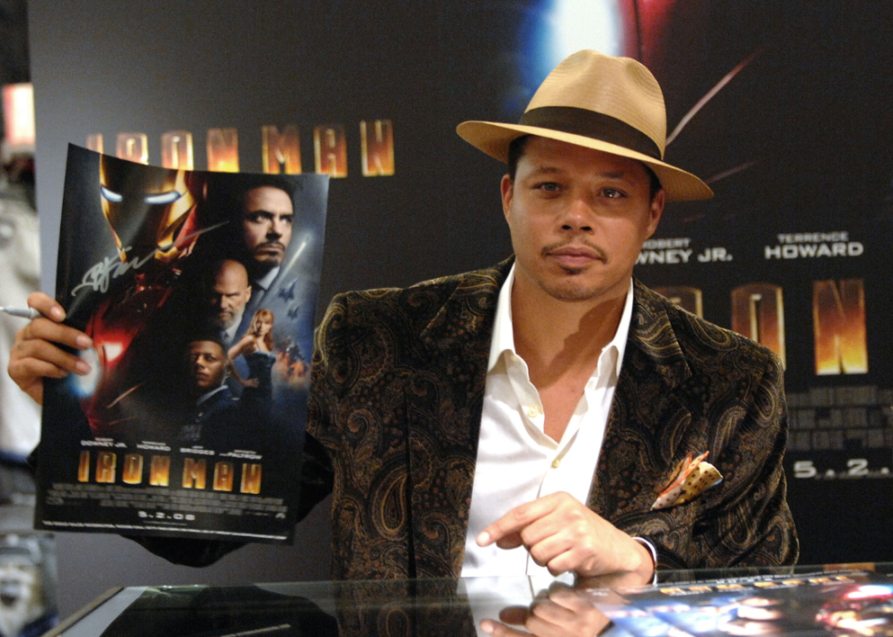 Terrence Howard holding a movie poster for Iron Man.